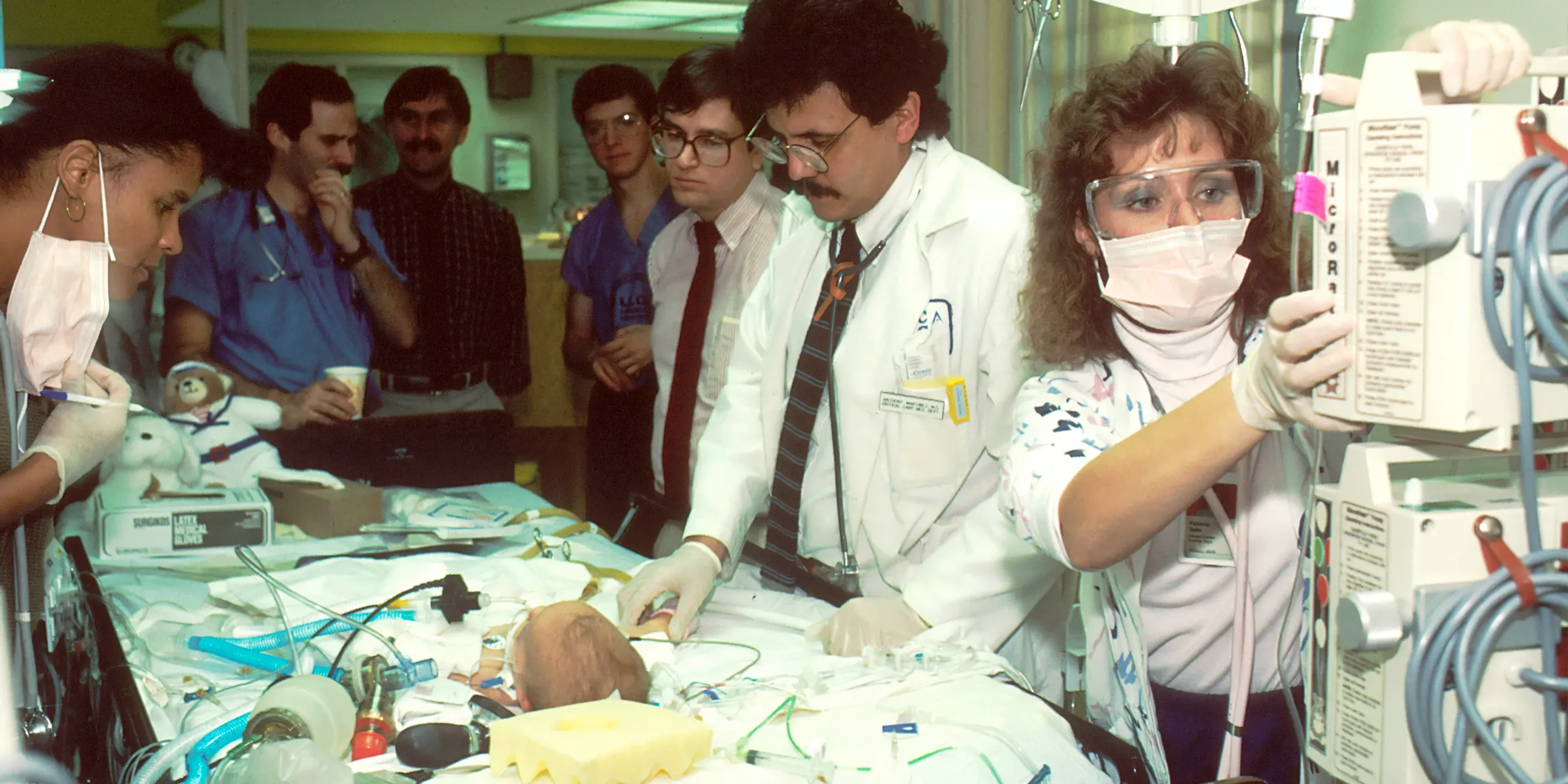 people beside baby lying on bed with medical apparatuses