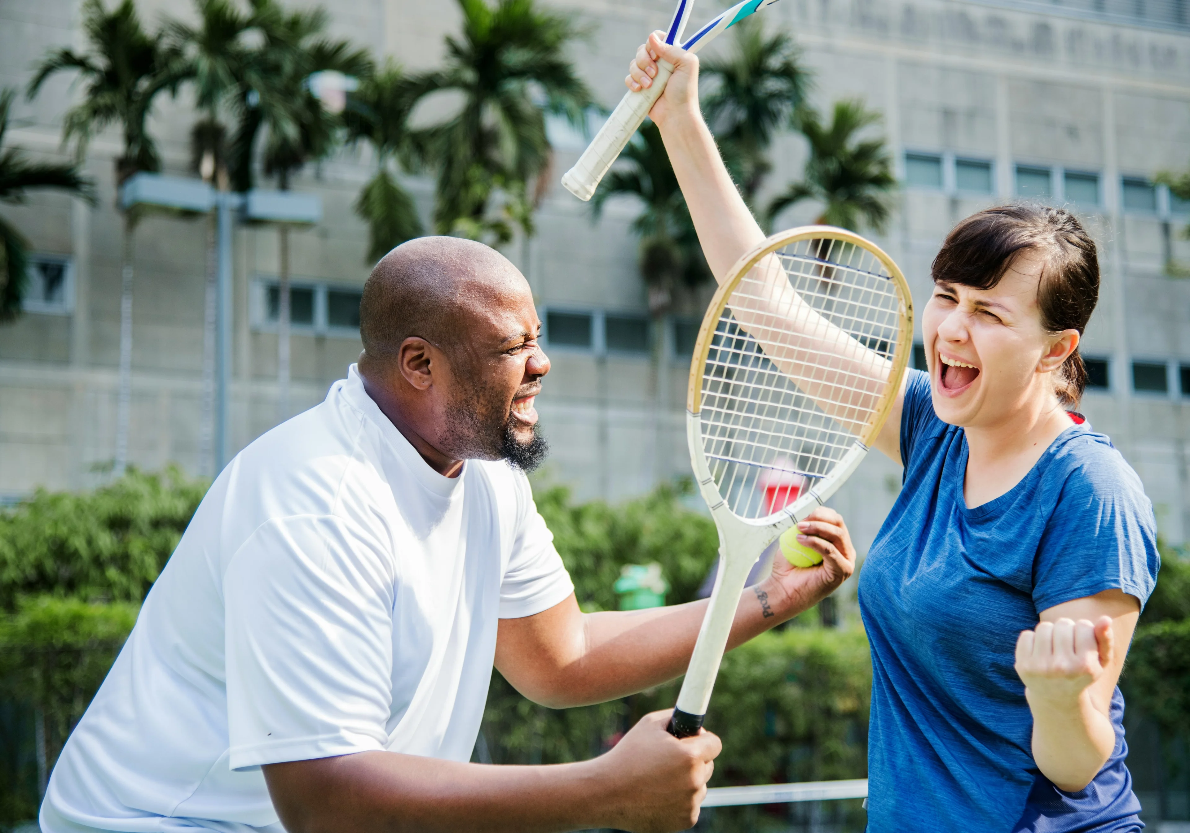 two very happy people celebrating while playing badminton
