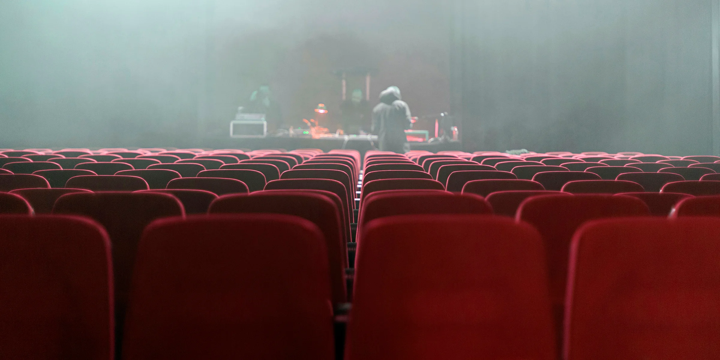 people sitting on red chairs watching a band performing on stage.