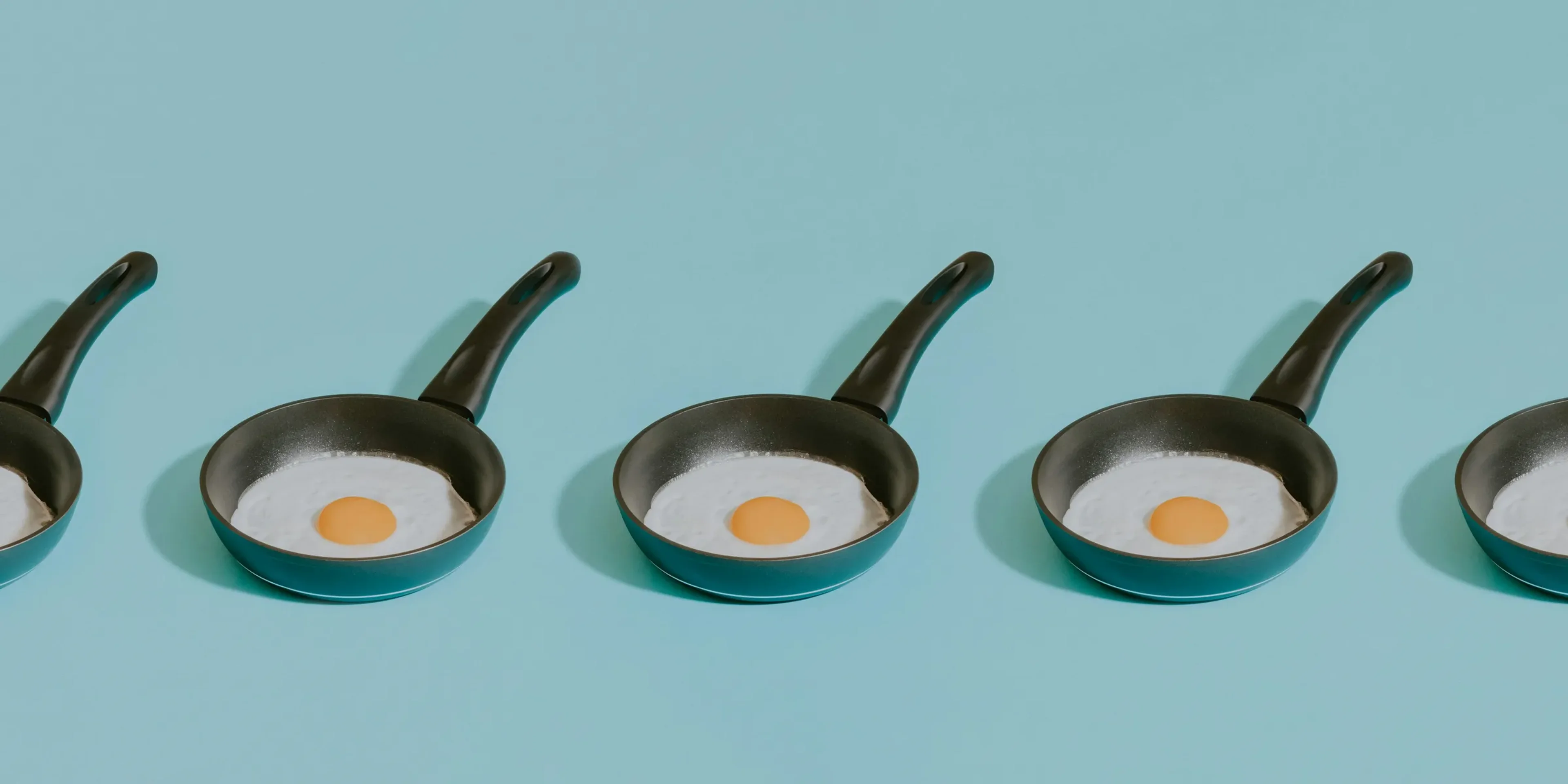 four frying pans with an egg in them