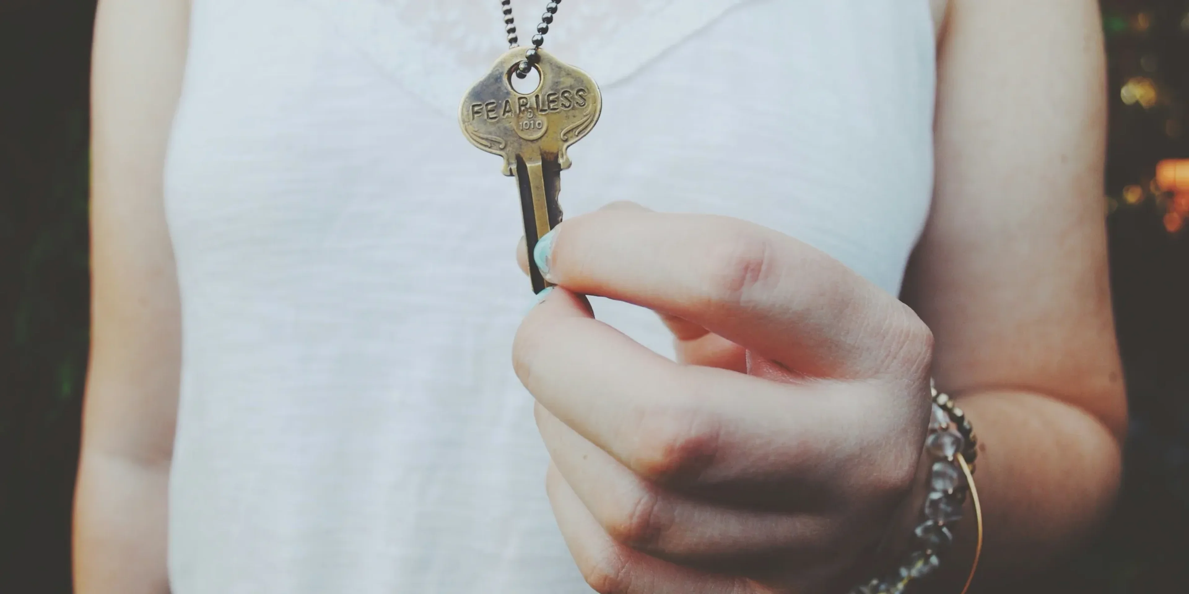 person holding gold-colored key pendant