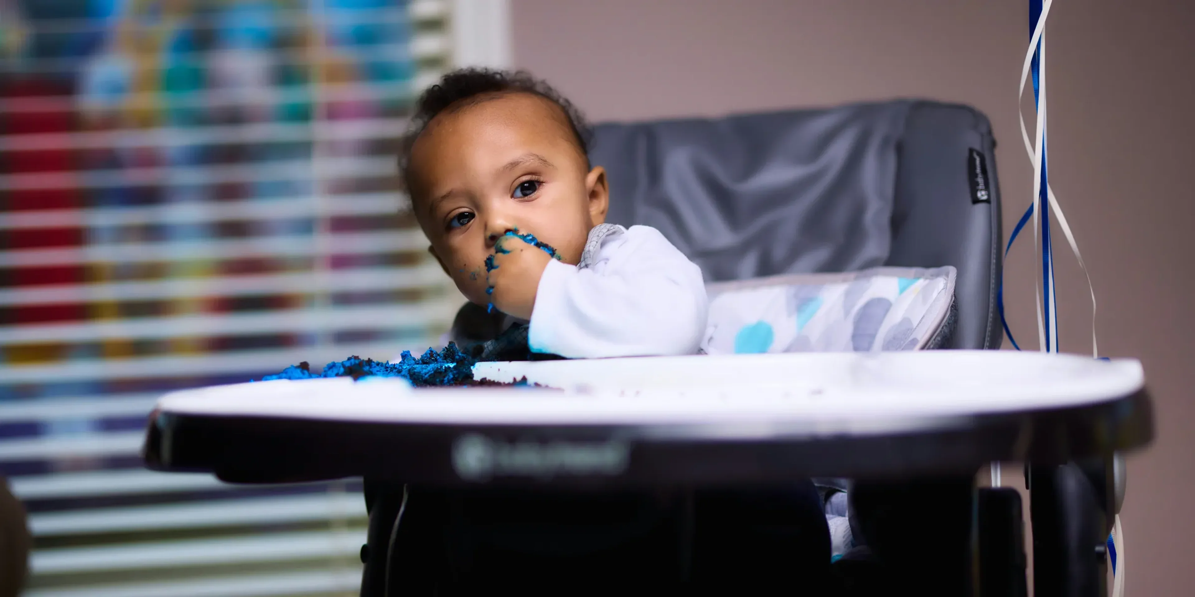 baby in white long sleeve shirt sitting on white high chair