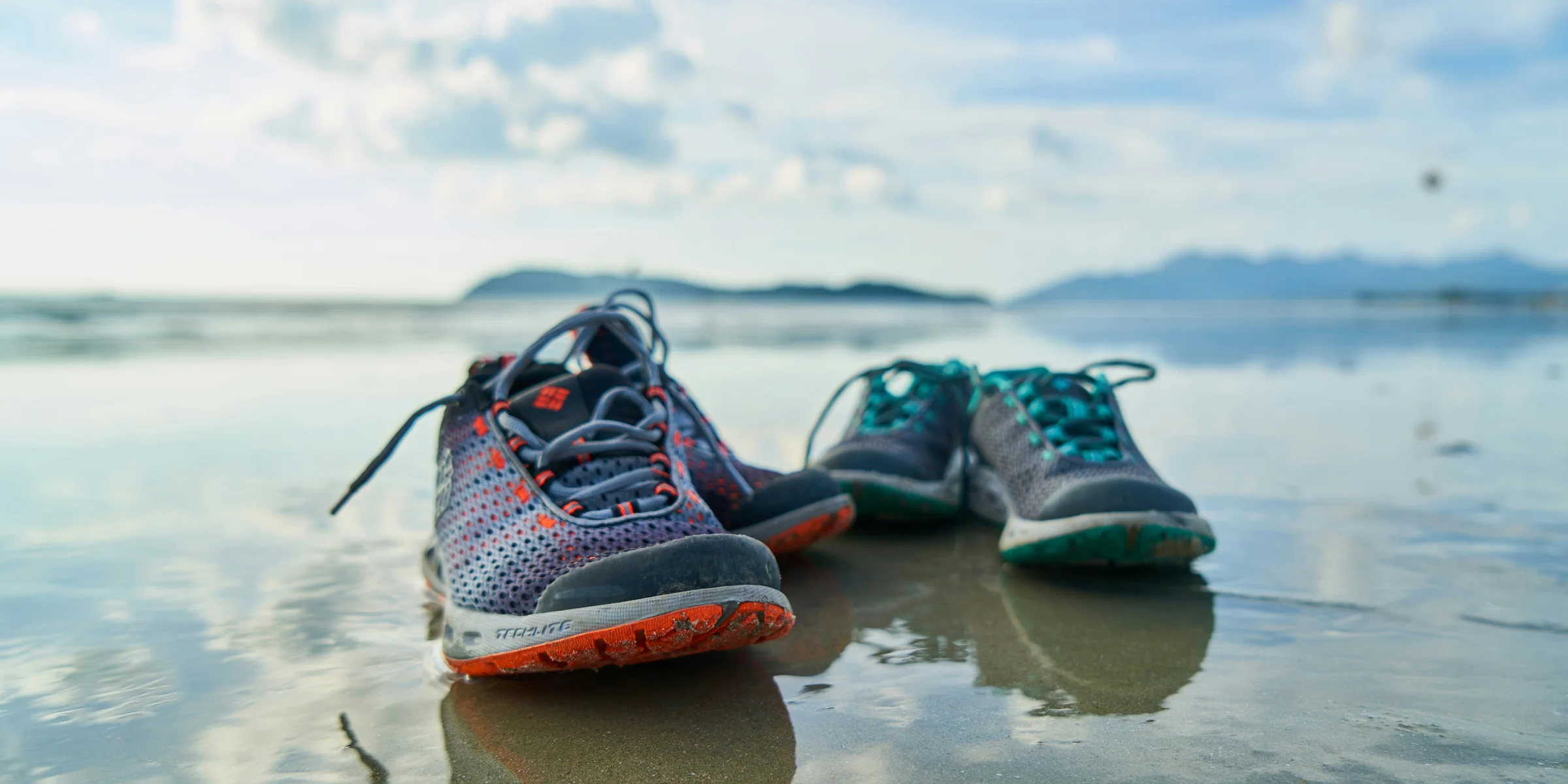 blue and black nike athletic shoes on brown sand during daytime.