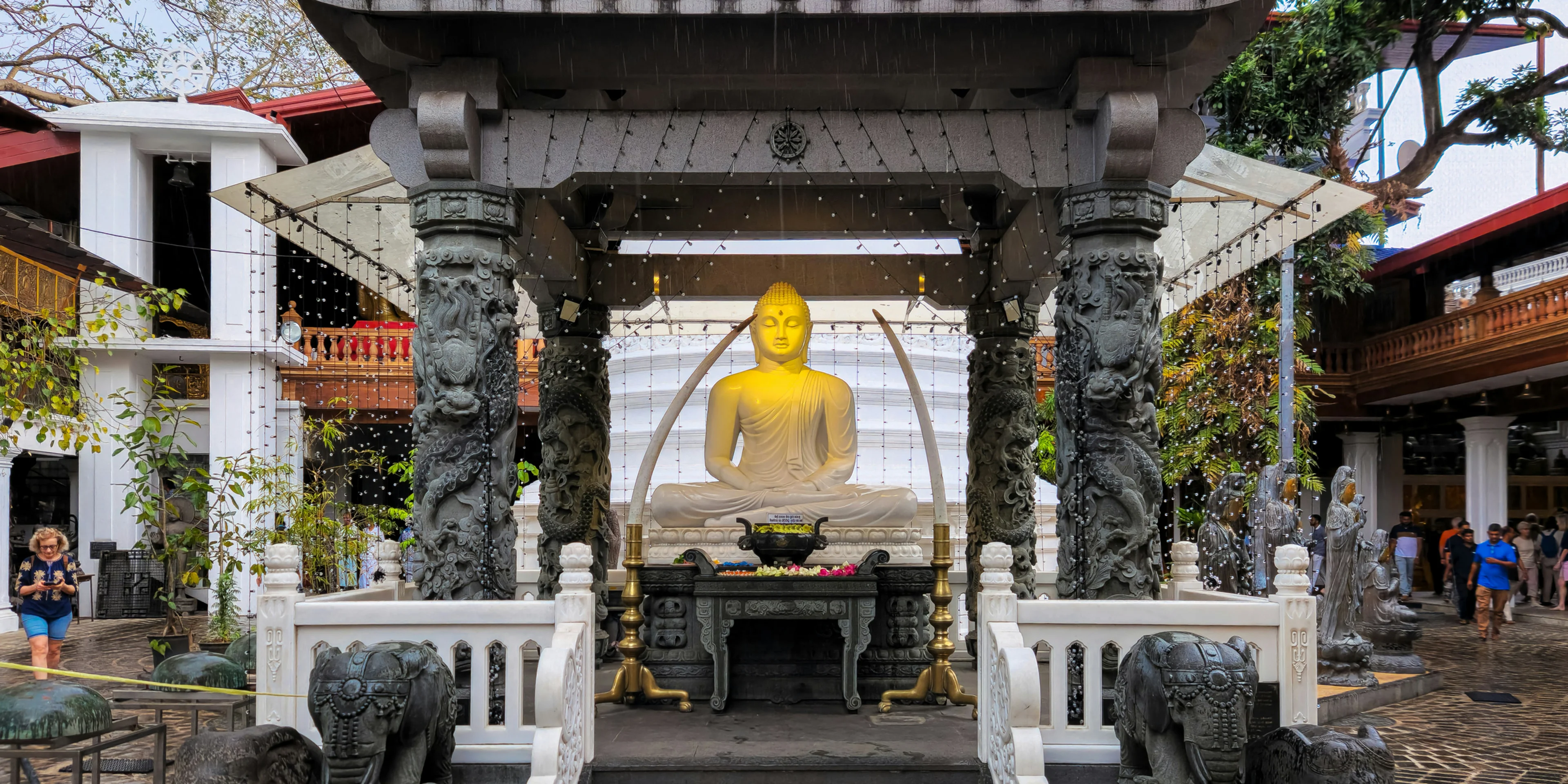 A golden buddha statue sits inside a pavilion..