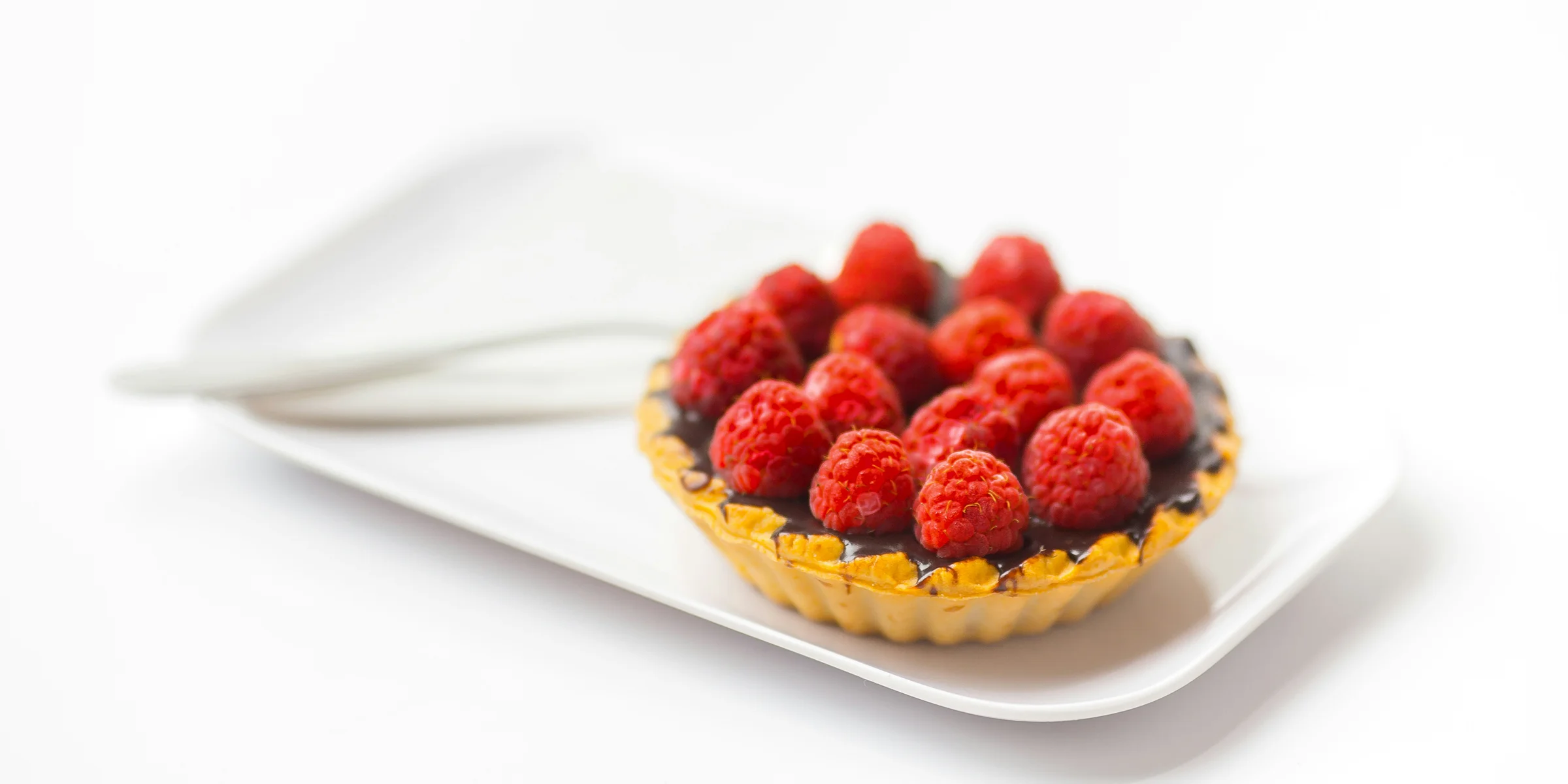 photo of chocolate cupcake with berry toppings on white ceramic plate.