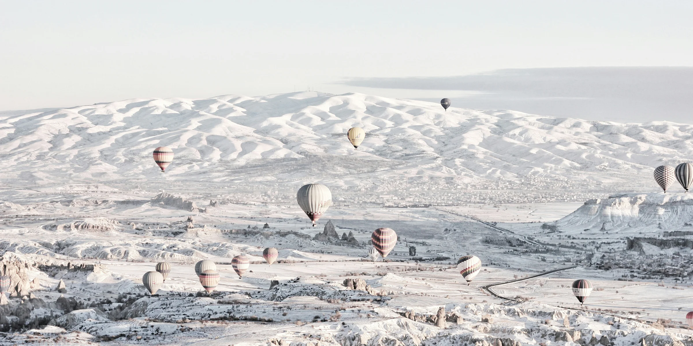 assorted-color air balloons below snowland at daytime