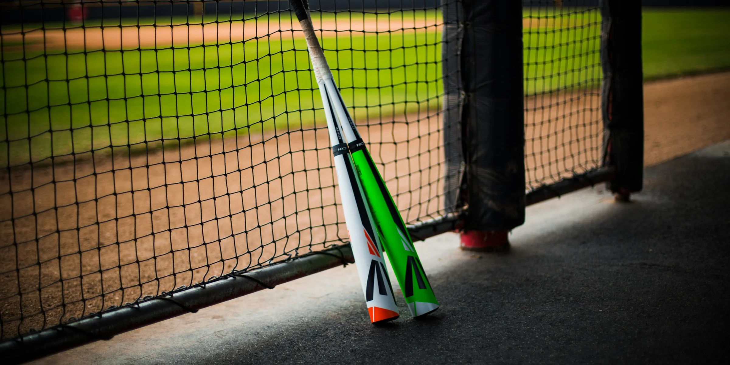a baseball bat leaning against a fence on a baseball field