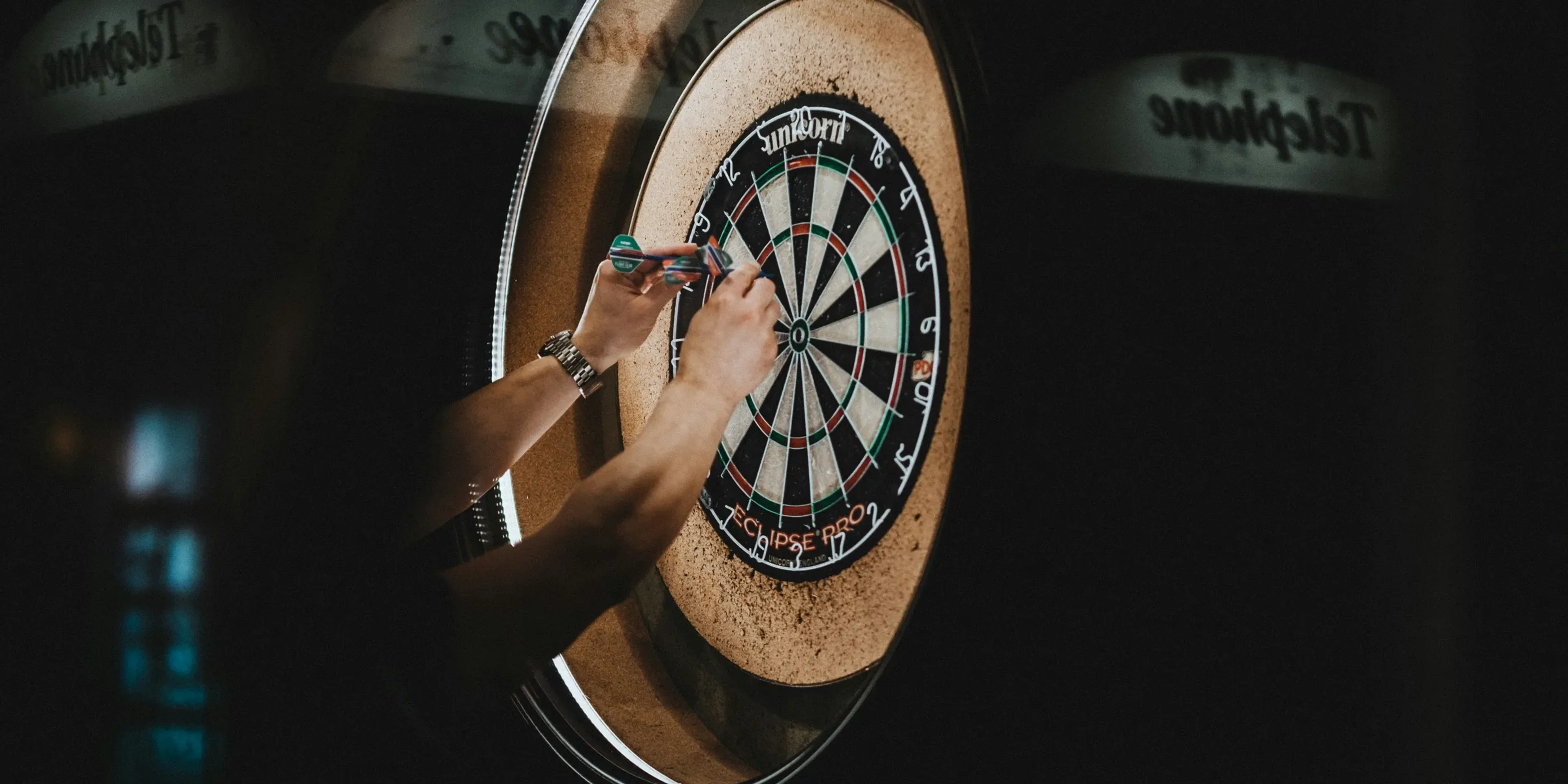 person picking dart pins on board