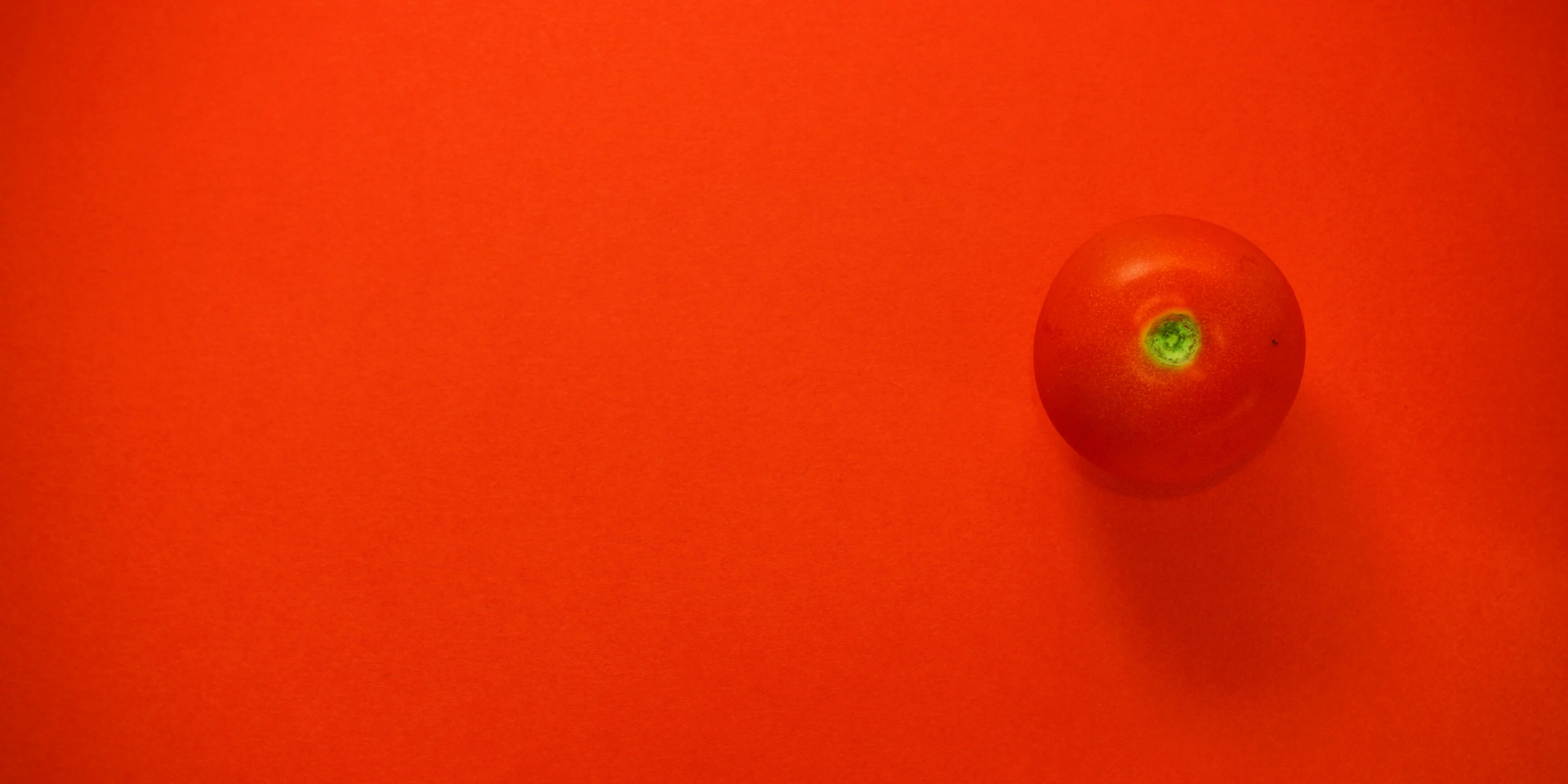 a tomato on a red surface with a green light.