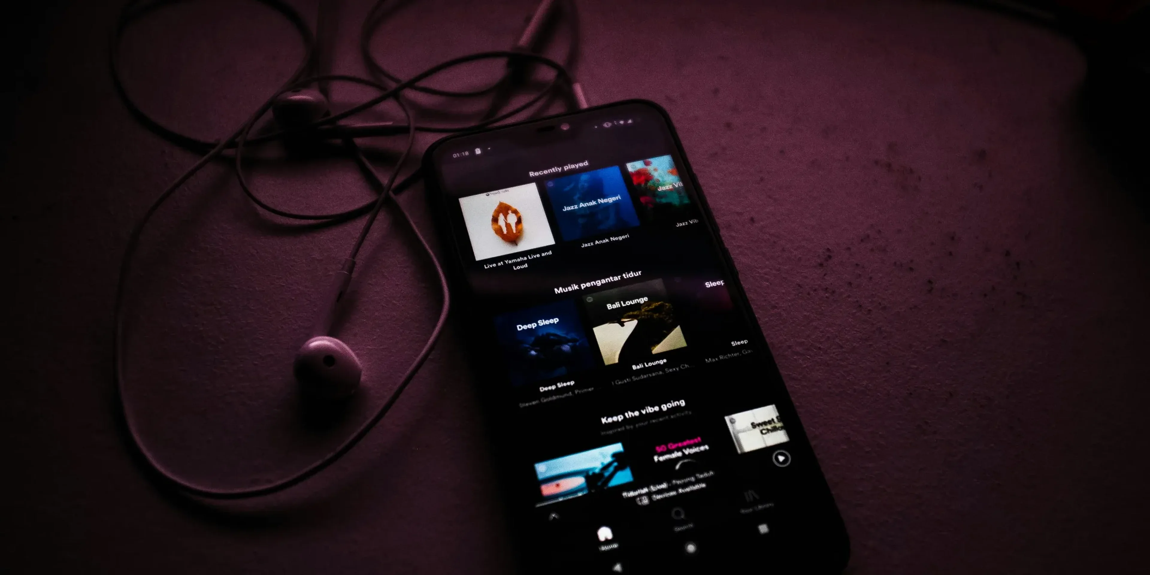 turned-on smartphone beside earbuds