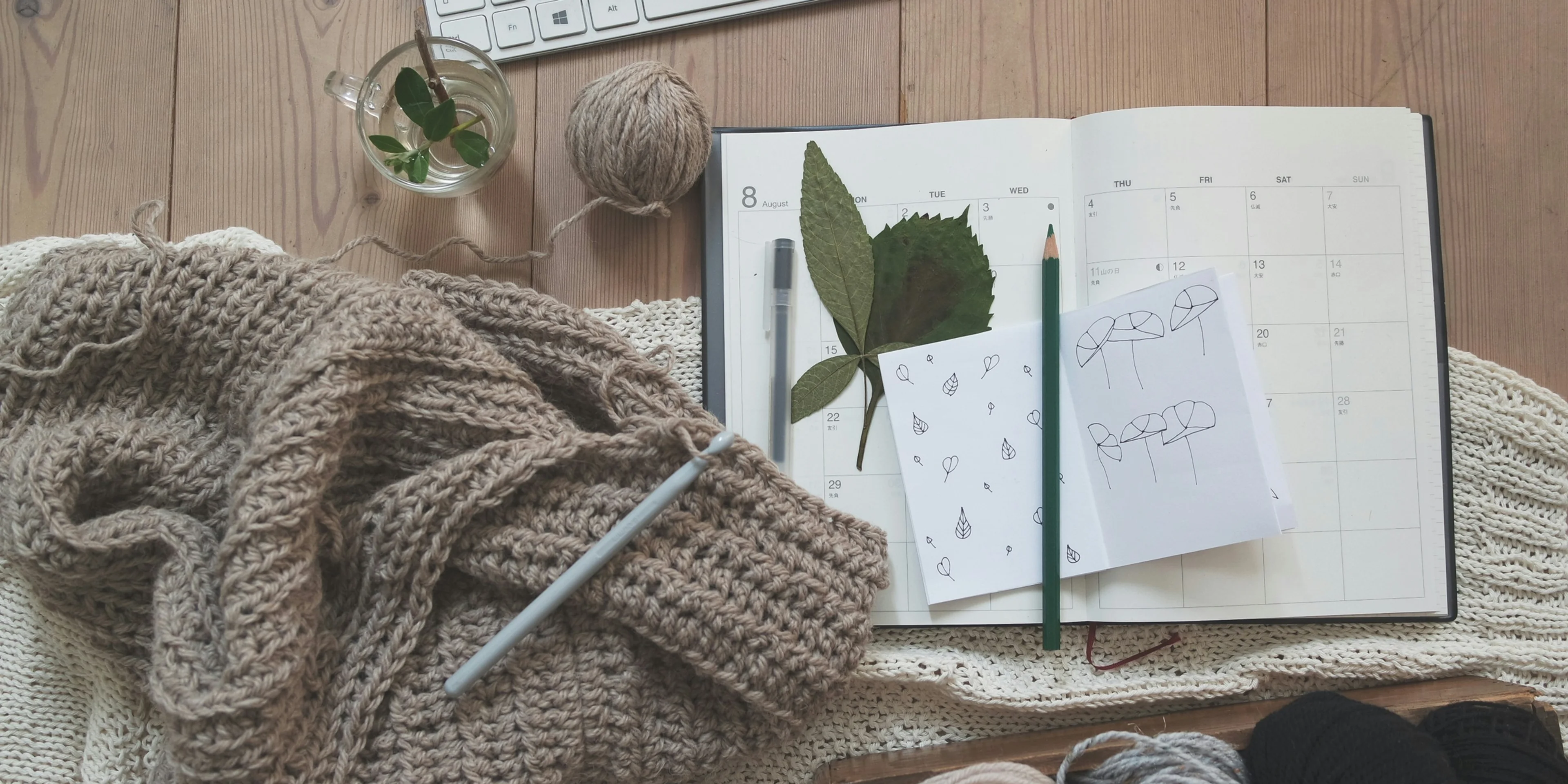 black pencil on white card beside brown knit textile