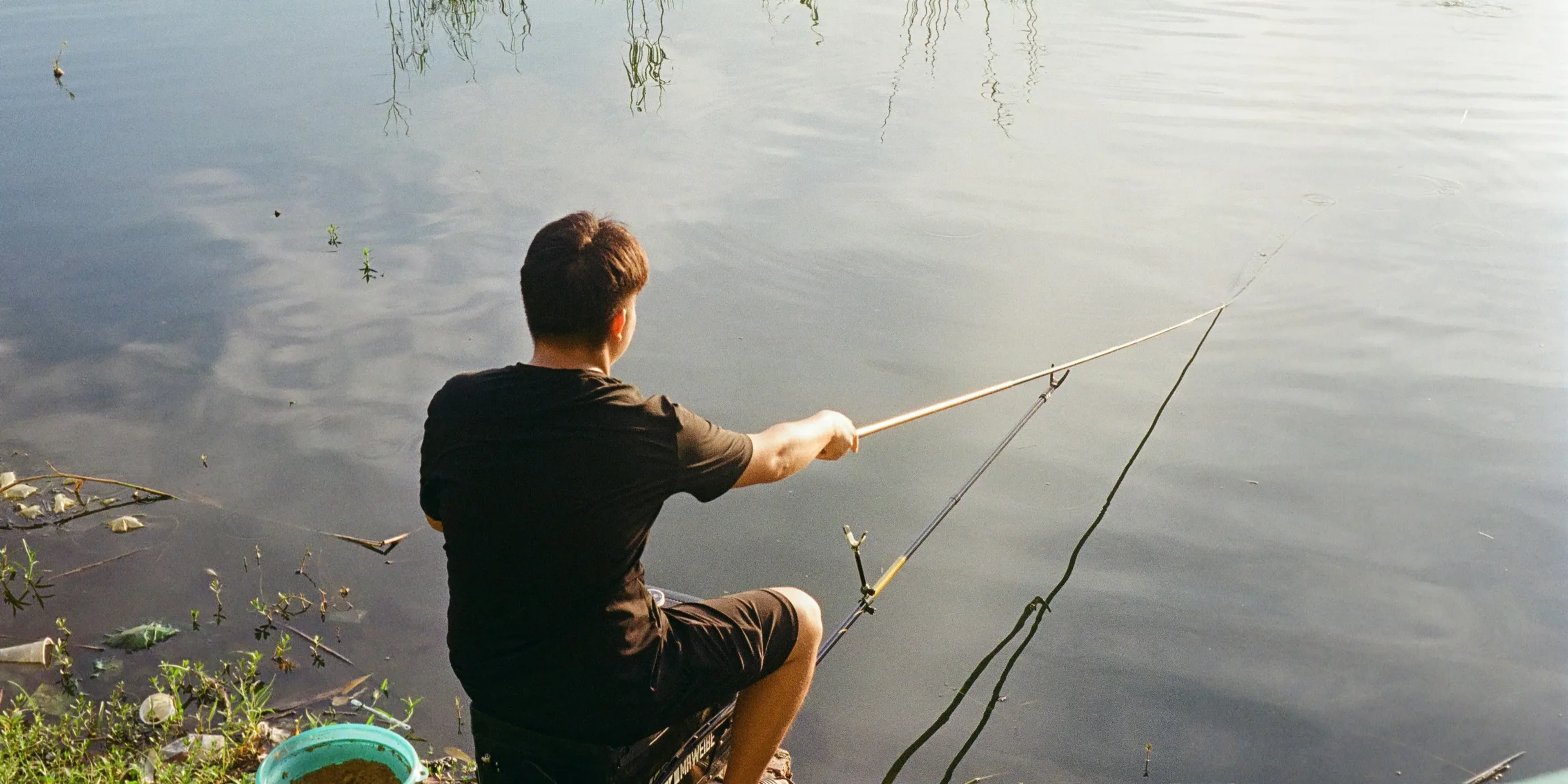 Man fishing by the water with a rod.
