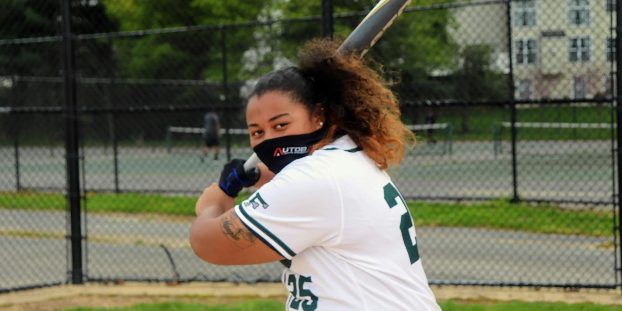 woman in white and blue jersey shirt holding baseball bat during daytime.