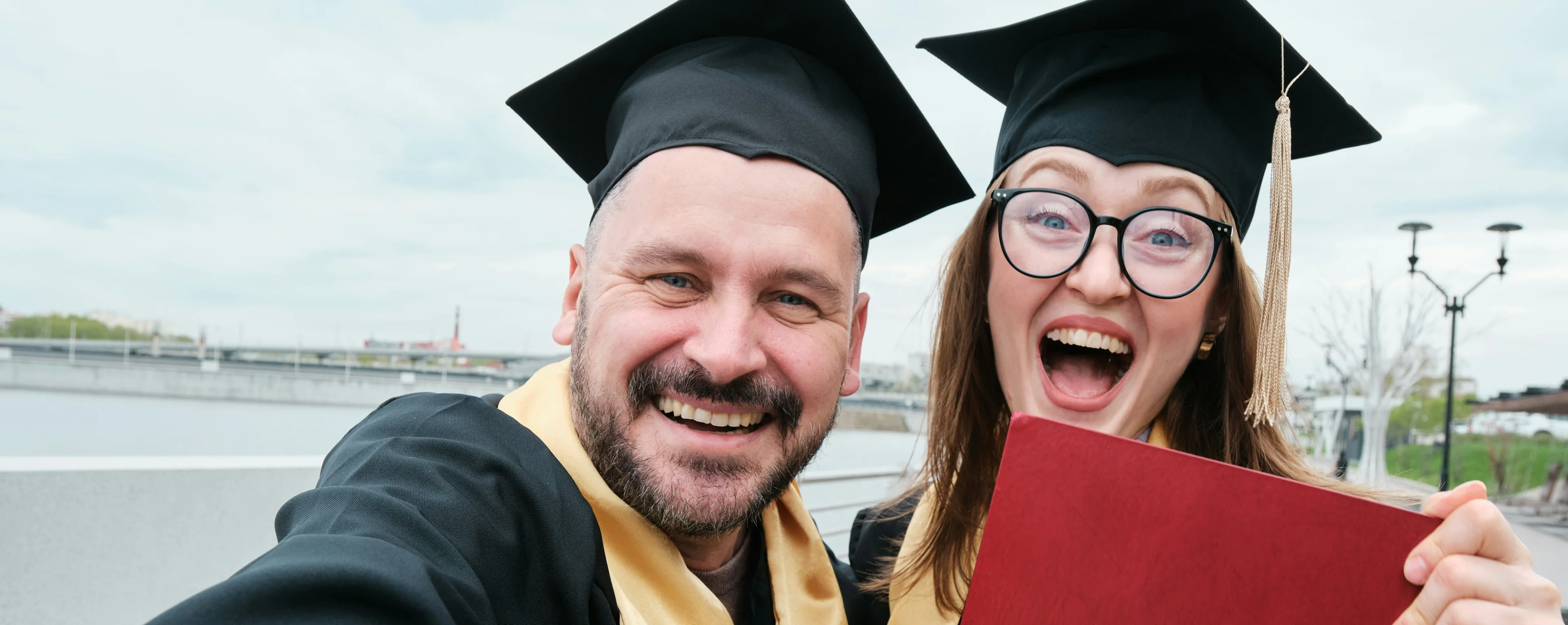 two happy grads showing off their diplomas