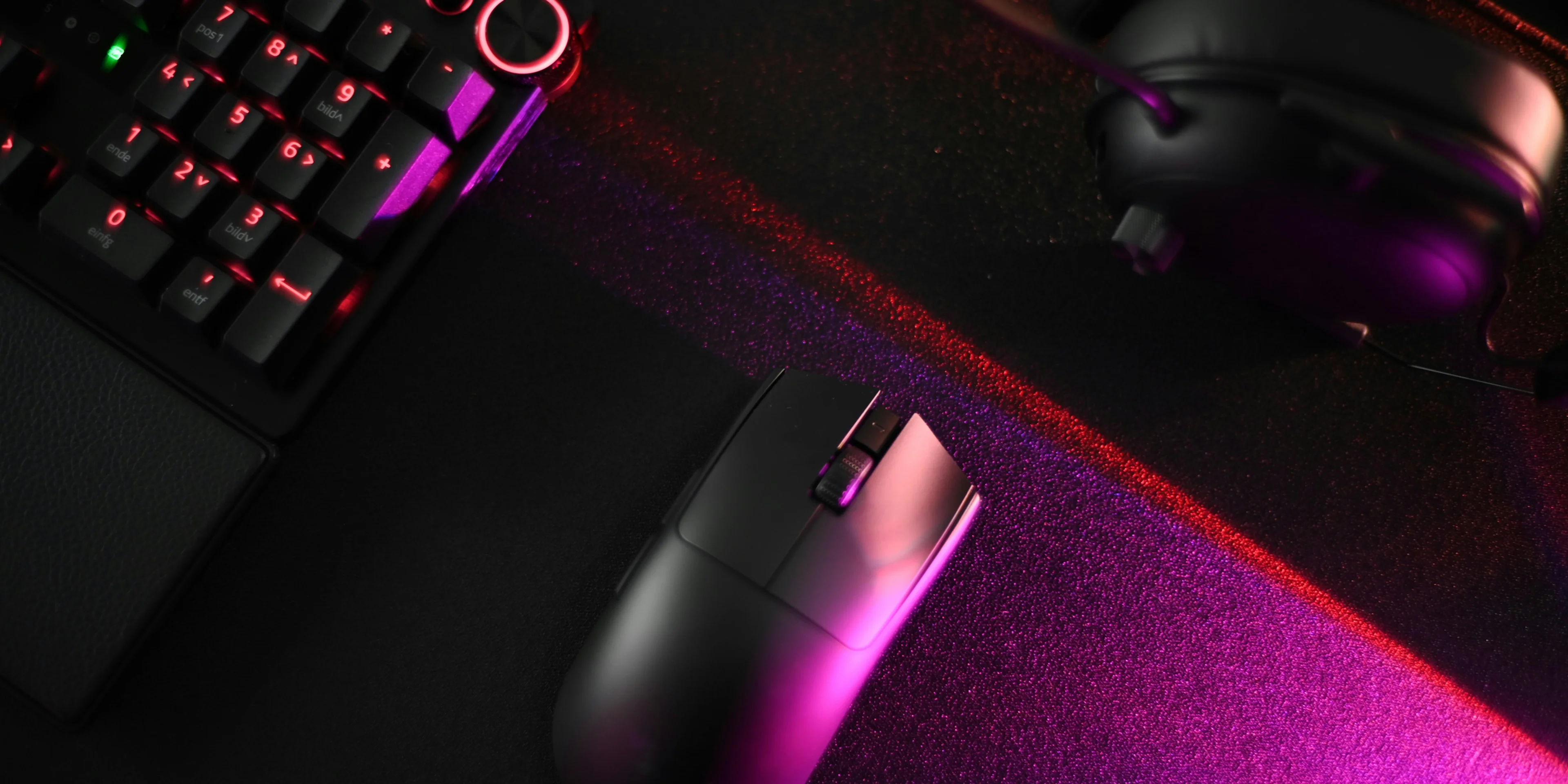 A computer keyboard, mouse, and headphones on a desk.