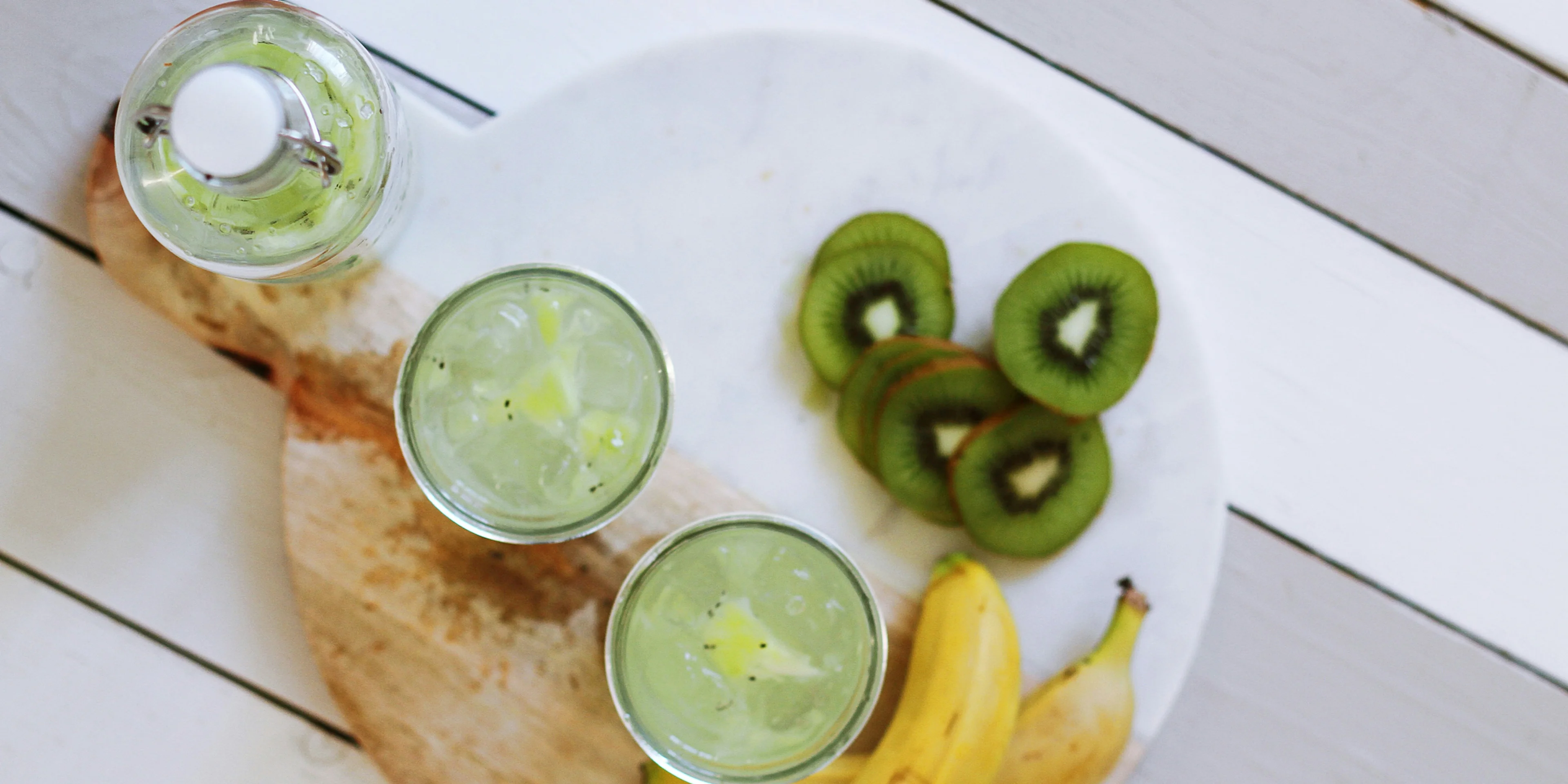 fruit juice cups beside yellow bananas on plate.