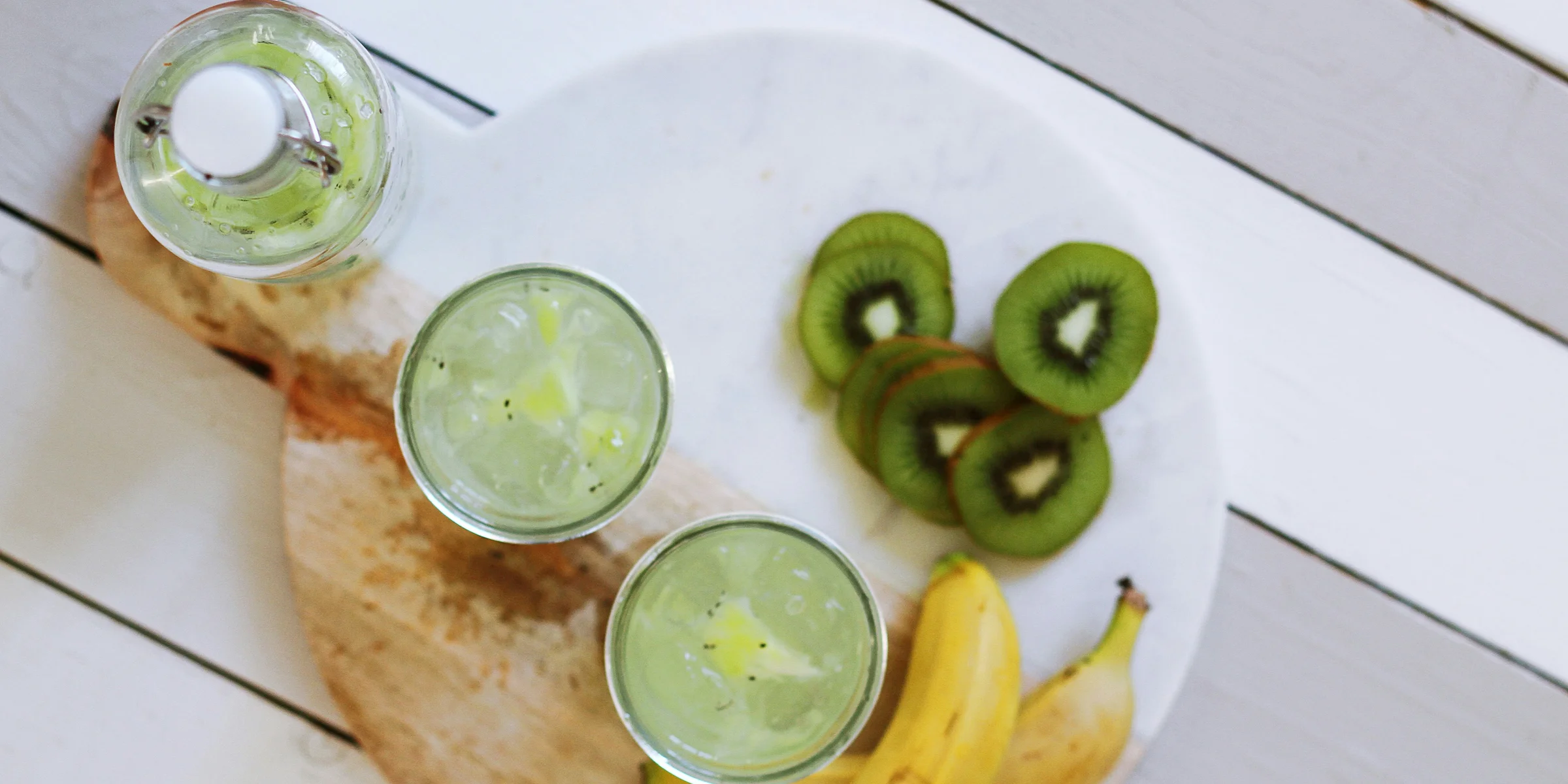 fruit juice cups beside yellow bananas on plate.
