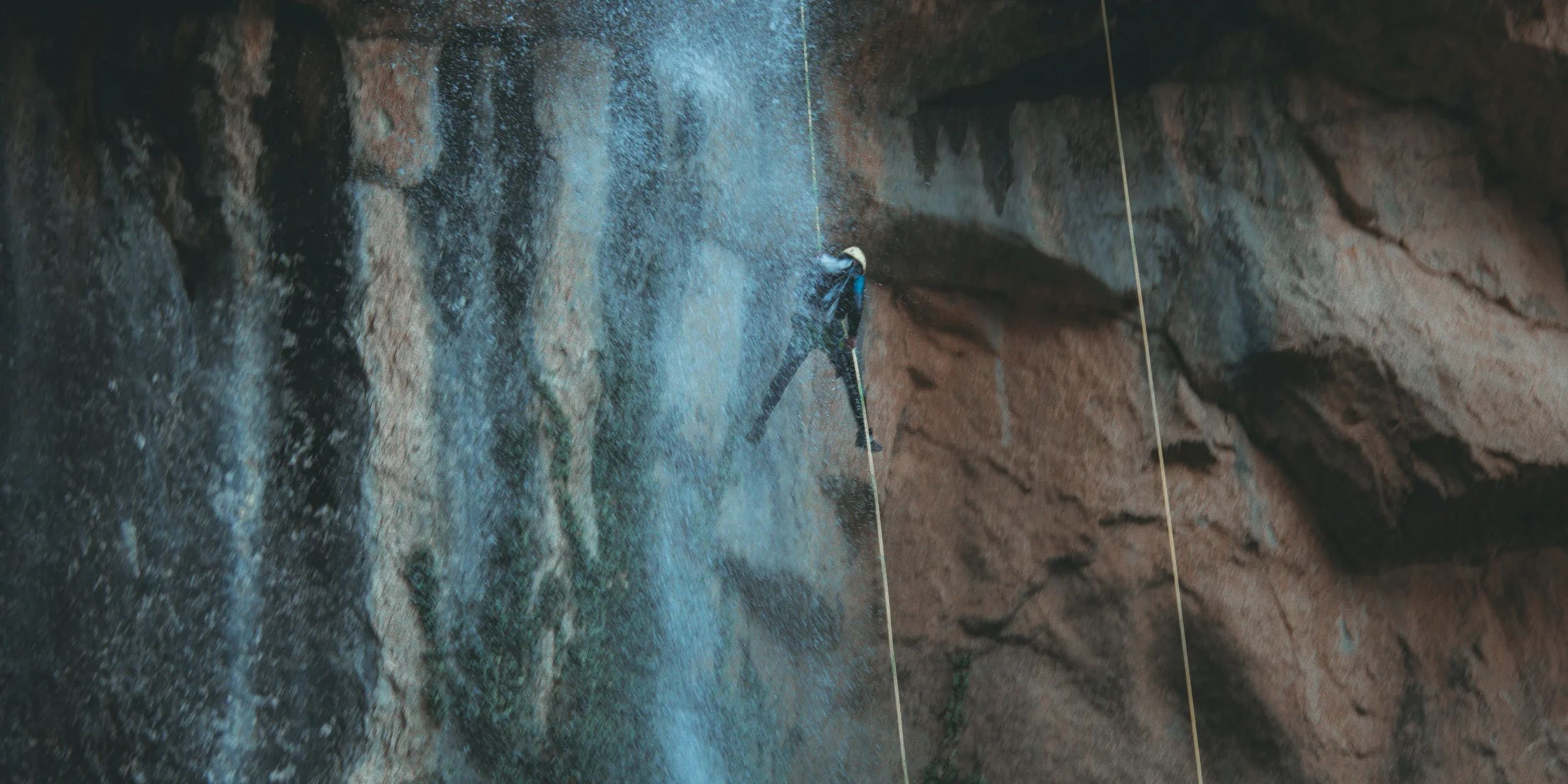 person in blue denim jeans and black shoes standing on gray rock.