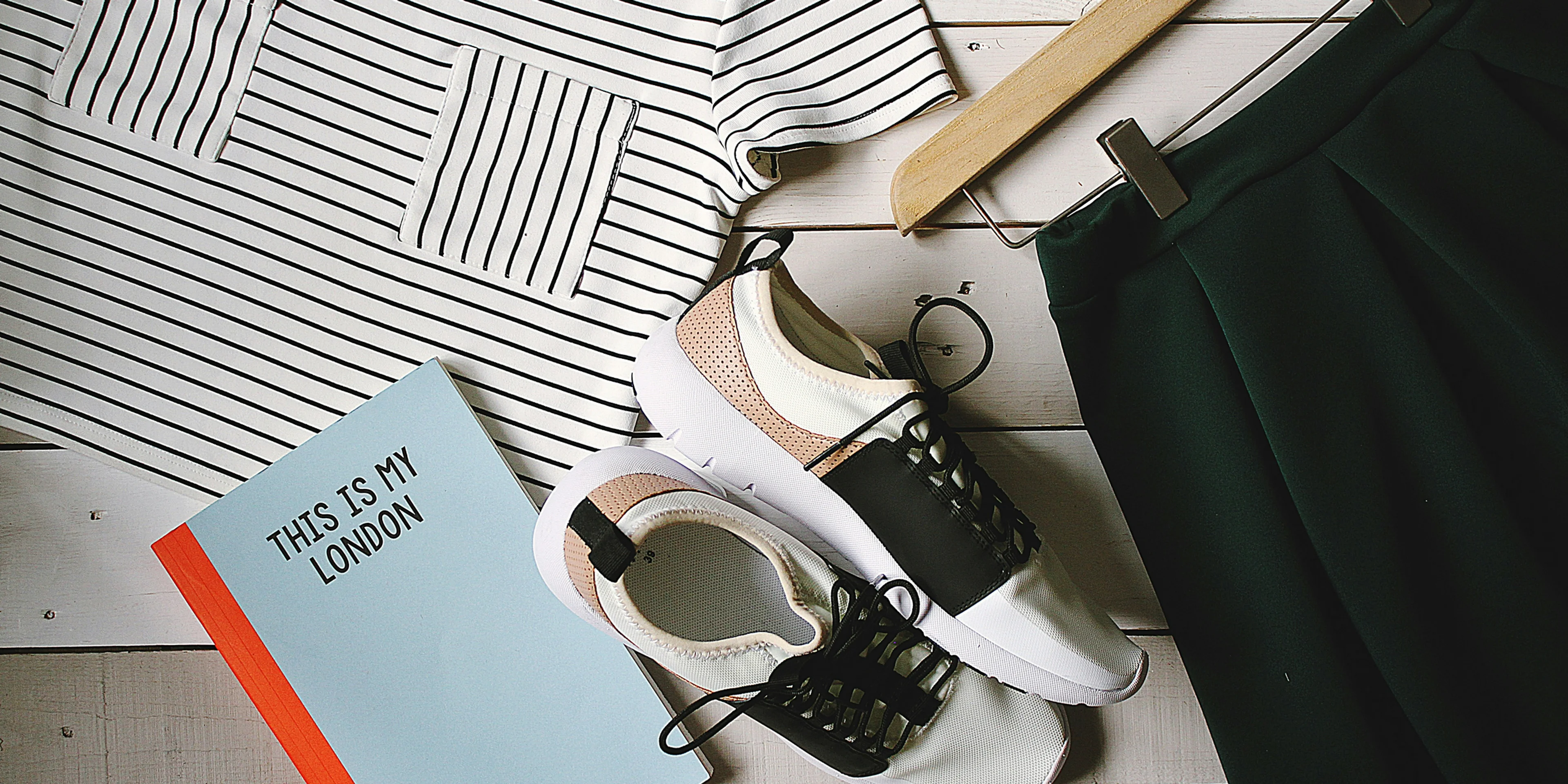pair of white-and-black low-top sneakers near black skirt on brown clothes hanger top view photography.