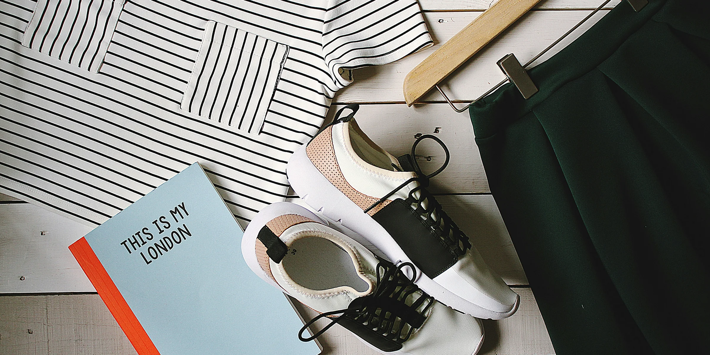 pair of white-and-black low-top sneakers near black skirt on brown clothes hanger top view photography.