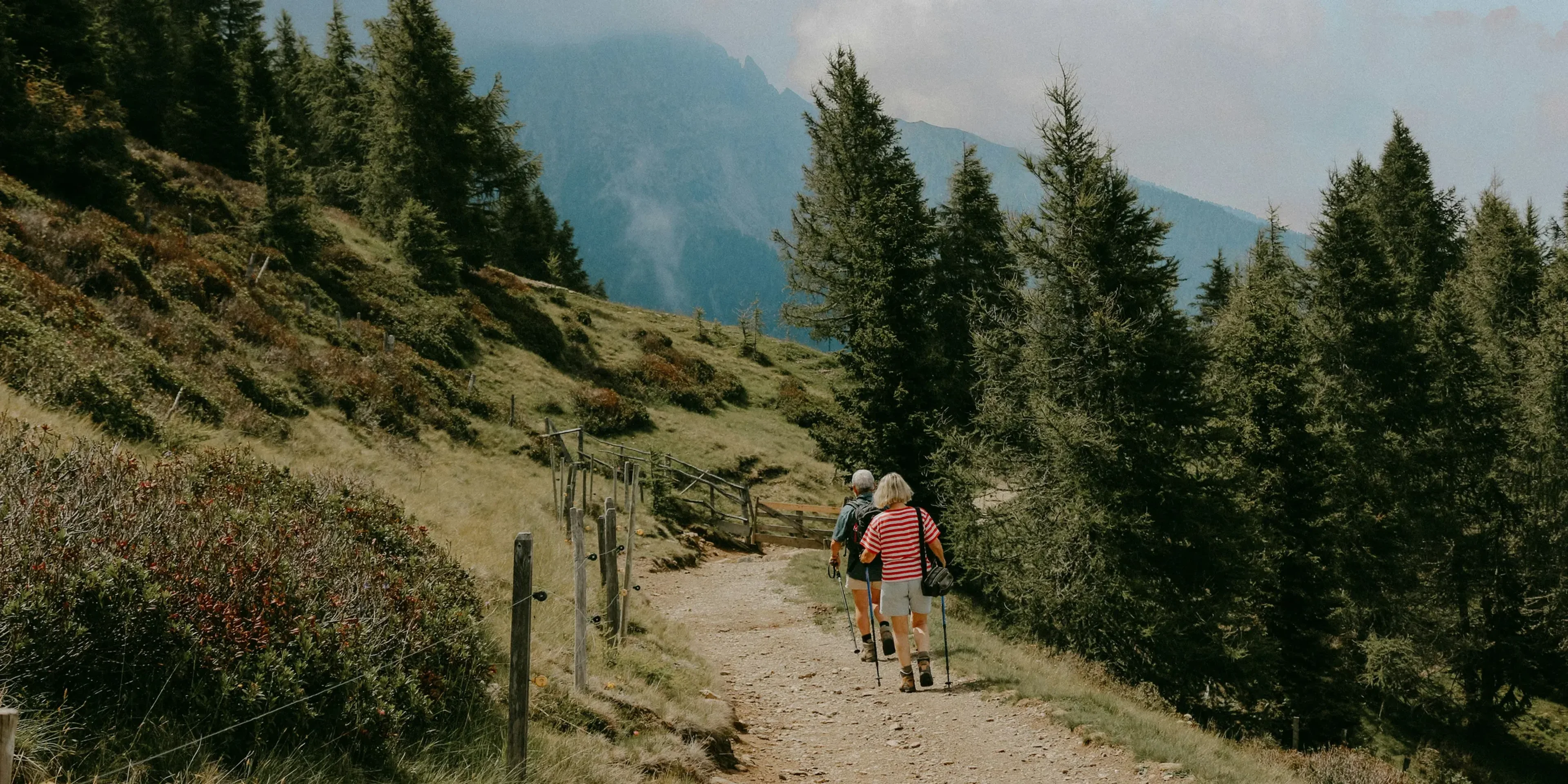 a couple of people hiking on a trail in the mountains
