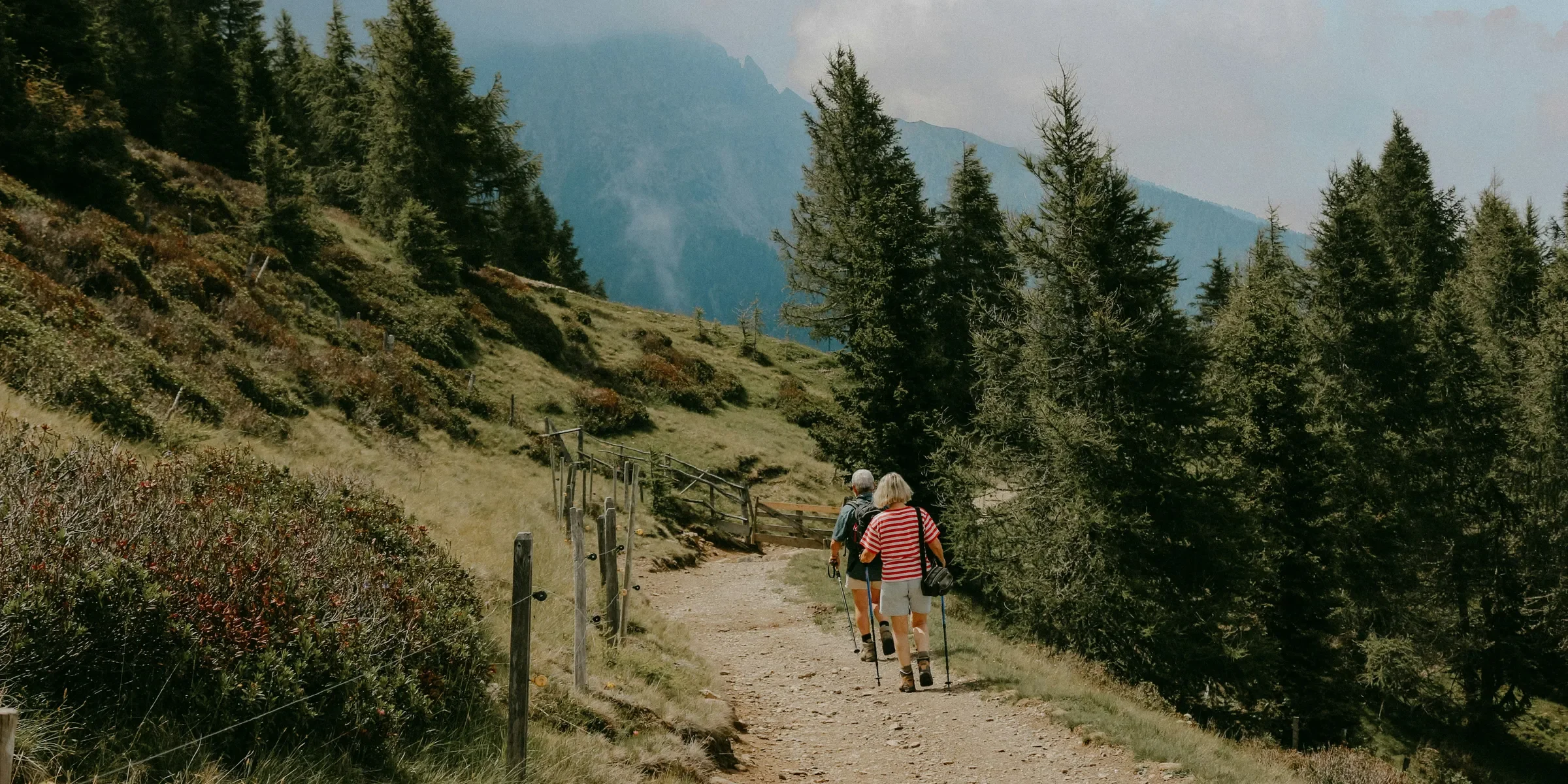 a couple of people hiking on a trail in the mountains