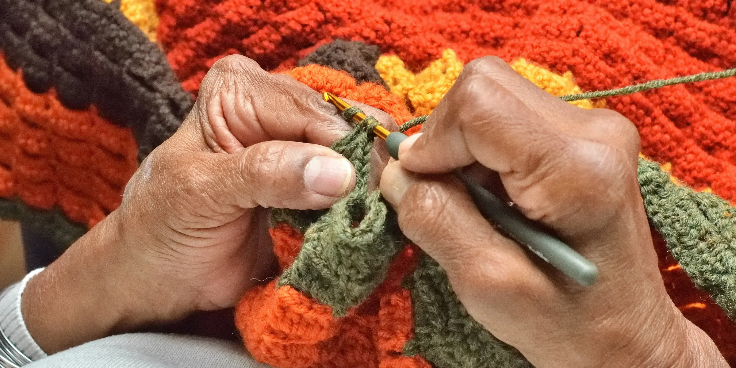 A person knitting a blanket with a pair of scissors