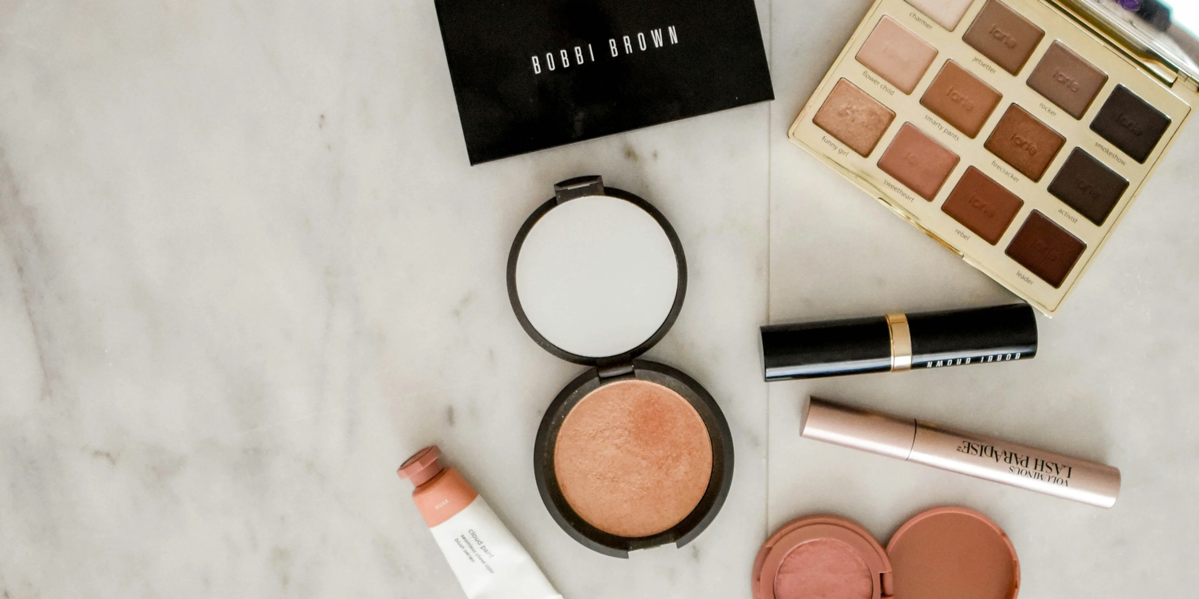 photo of assorted makeup products on gray surface.
