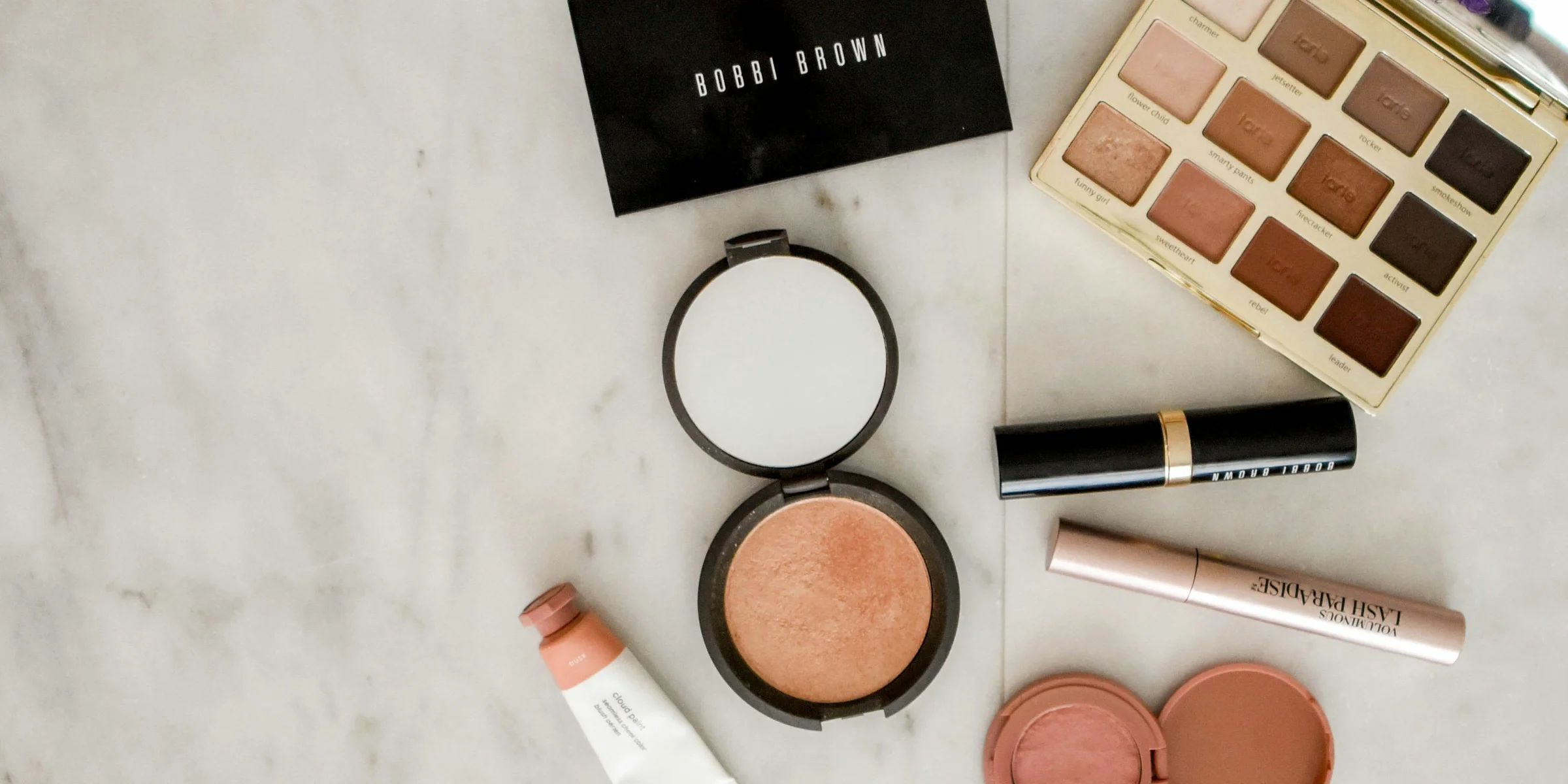 photo of assorted makeup products on gray surface.