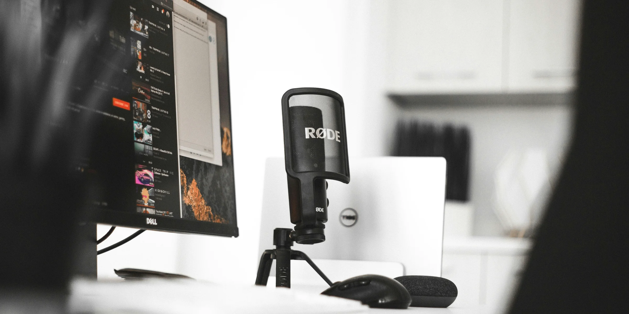 black Rode condenser microphone beside computer monitor.