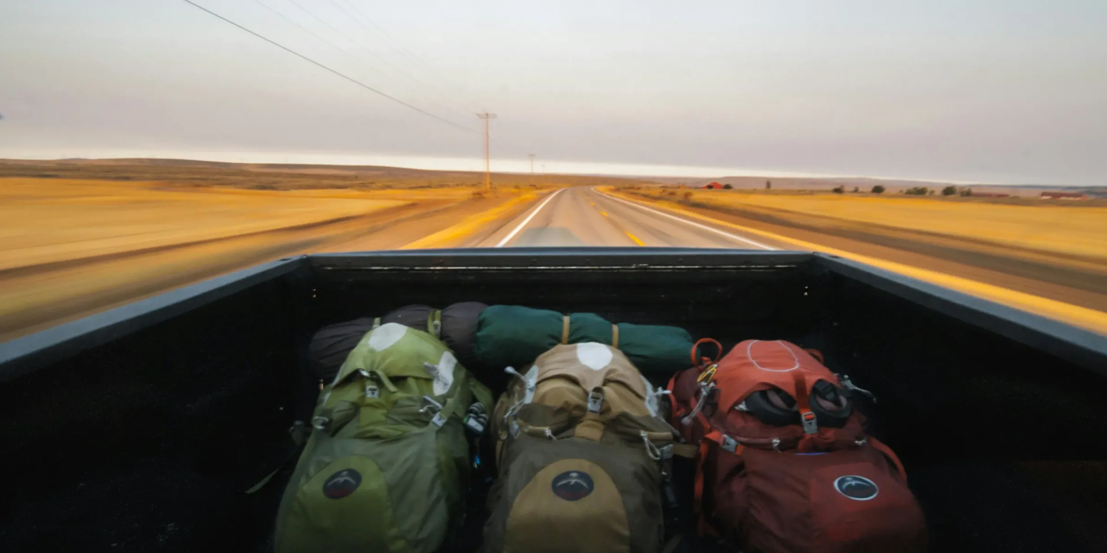photography of several hiking backpacks in truck bed