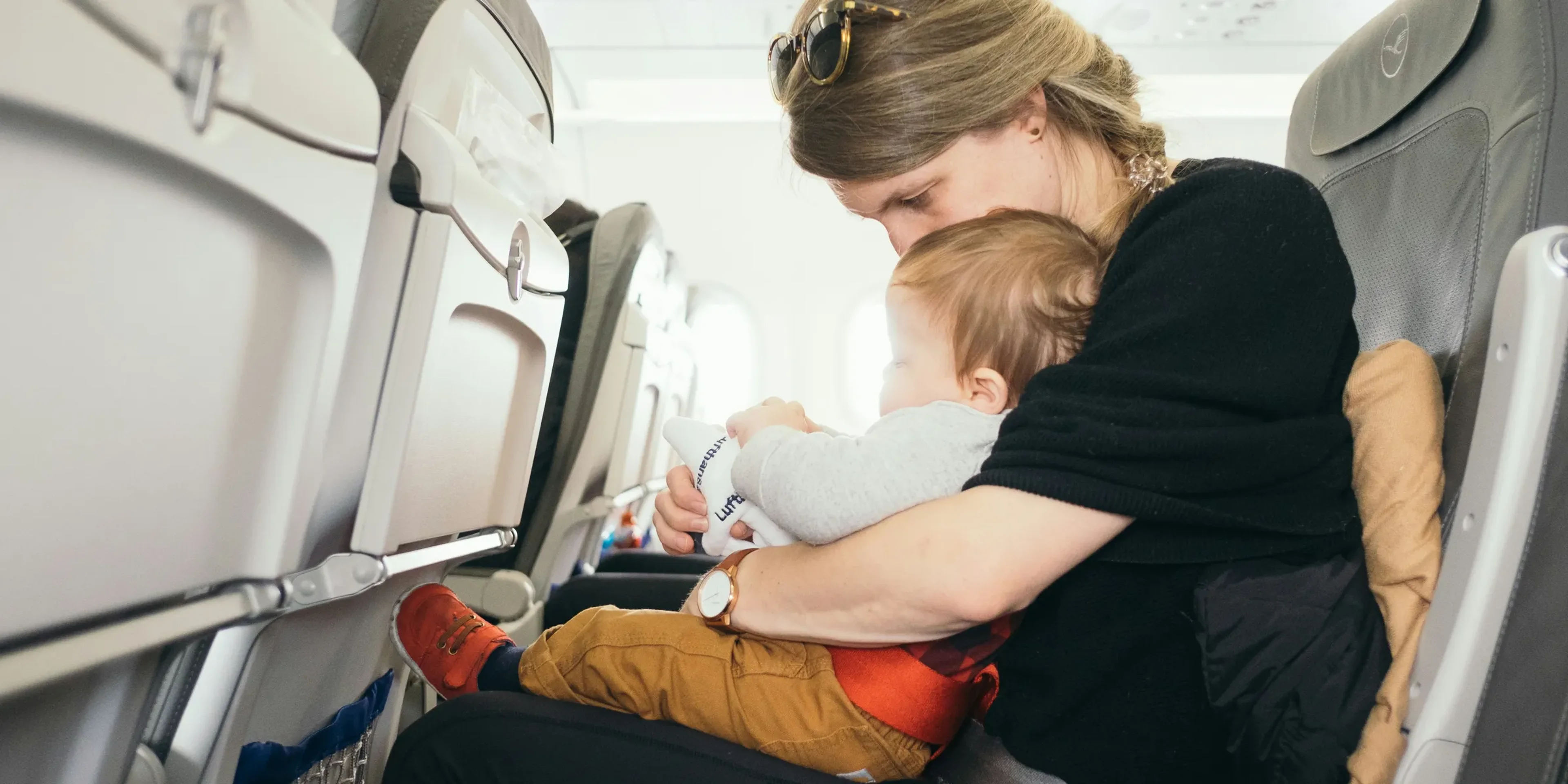 woman carrying baby while sitting on gray seat