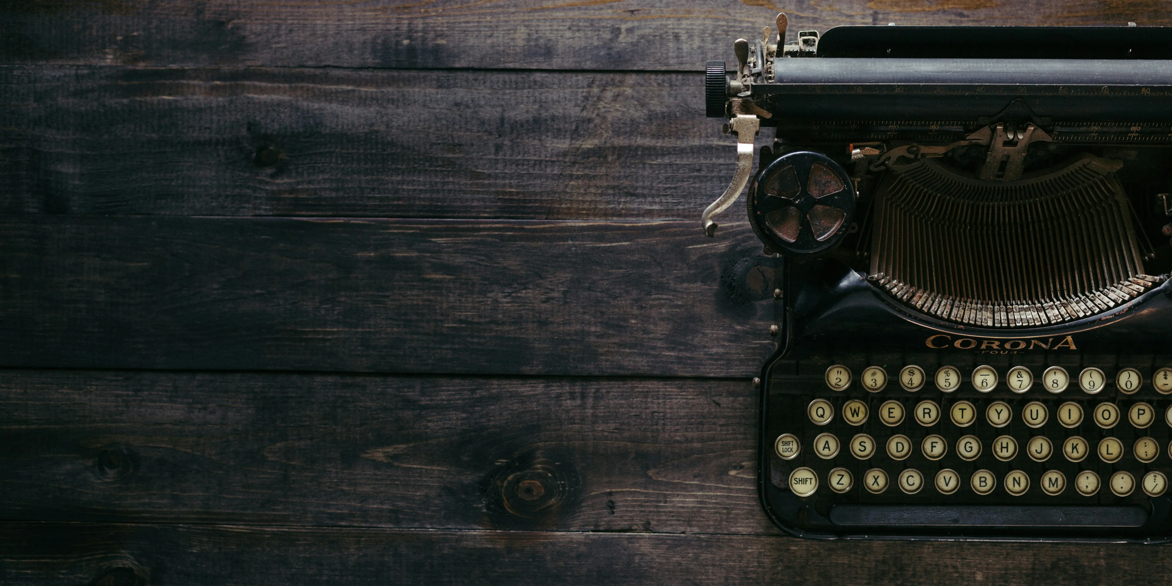 black Corona typewriter on brown wood planks.