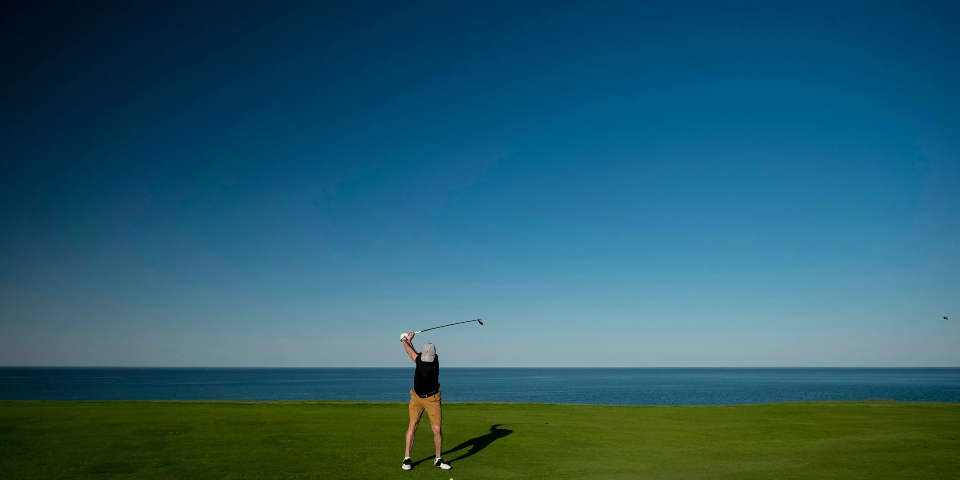 man standing on green grass field playing golf.