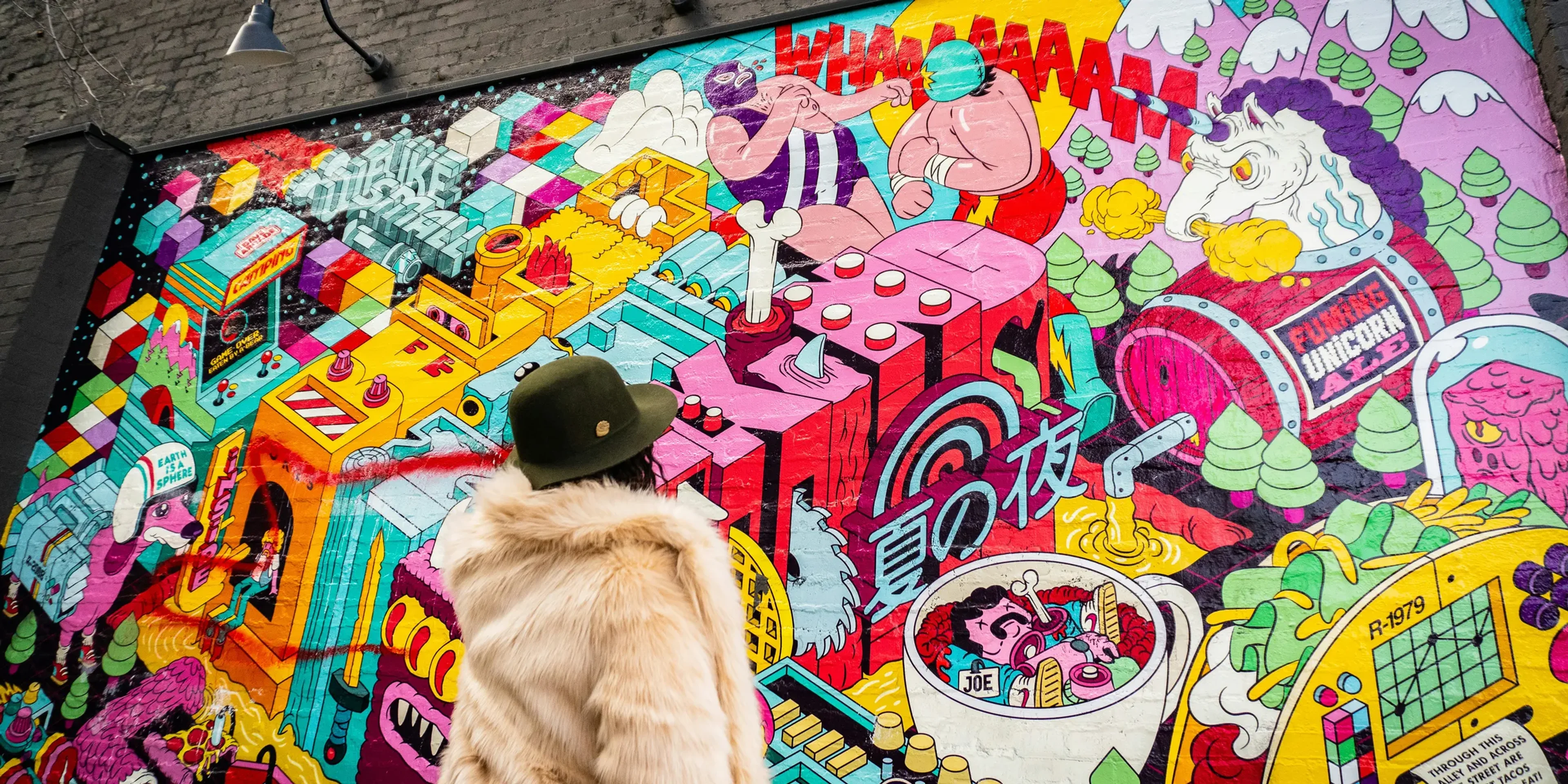 person wearing gray fur coat looking at graffiti during daytime