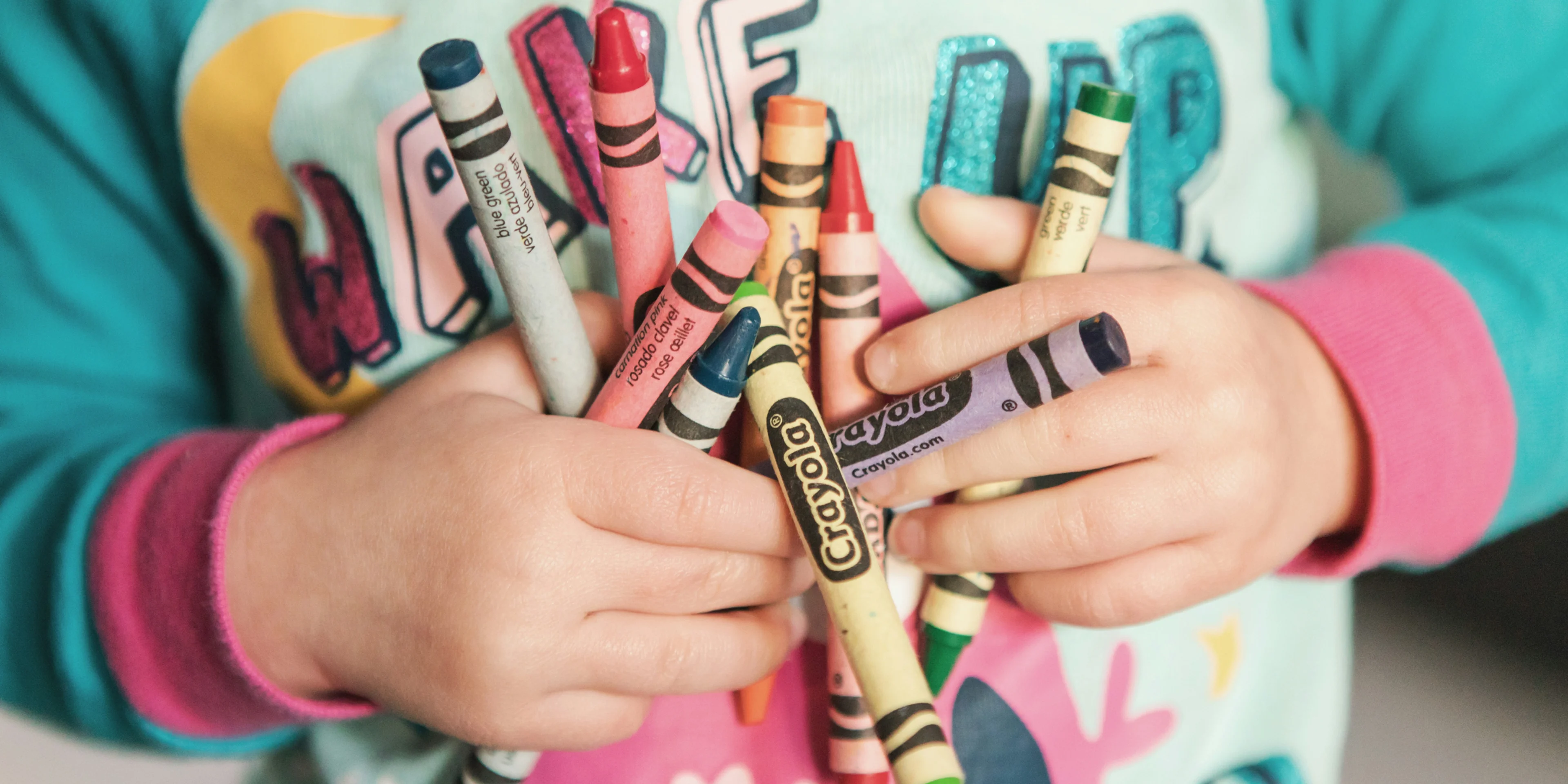 toddler holding assorted-color Crayola lot.