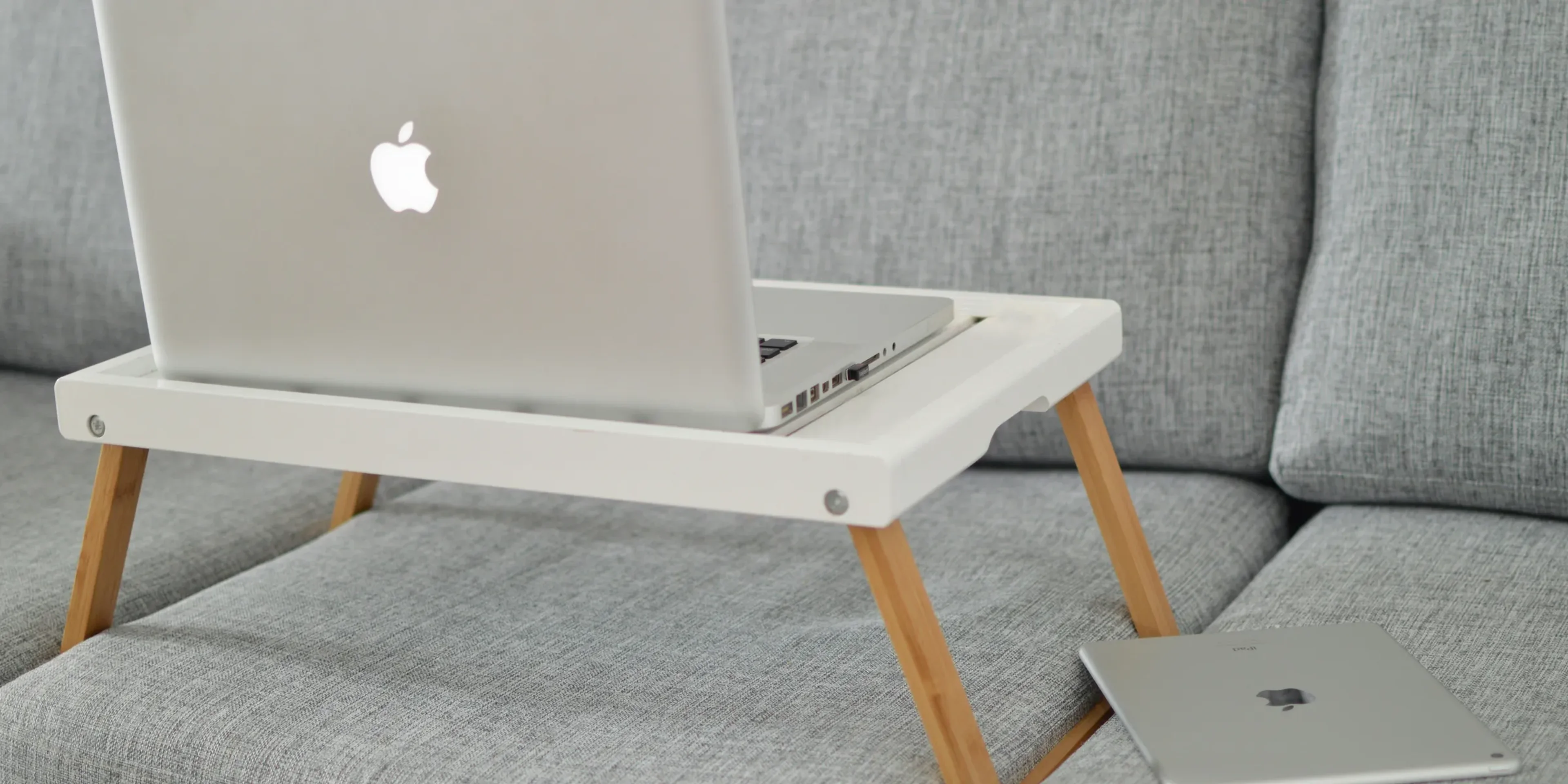 silver MacBook on laptop table on sofa