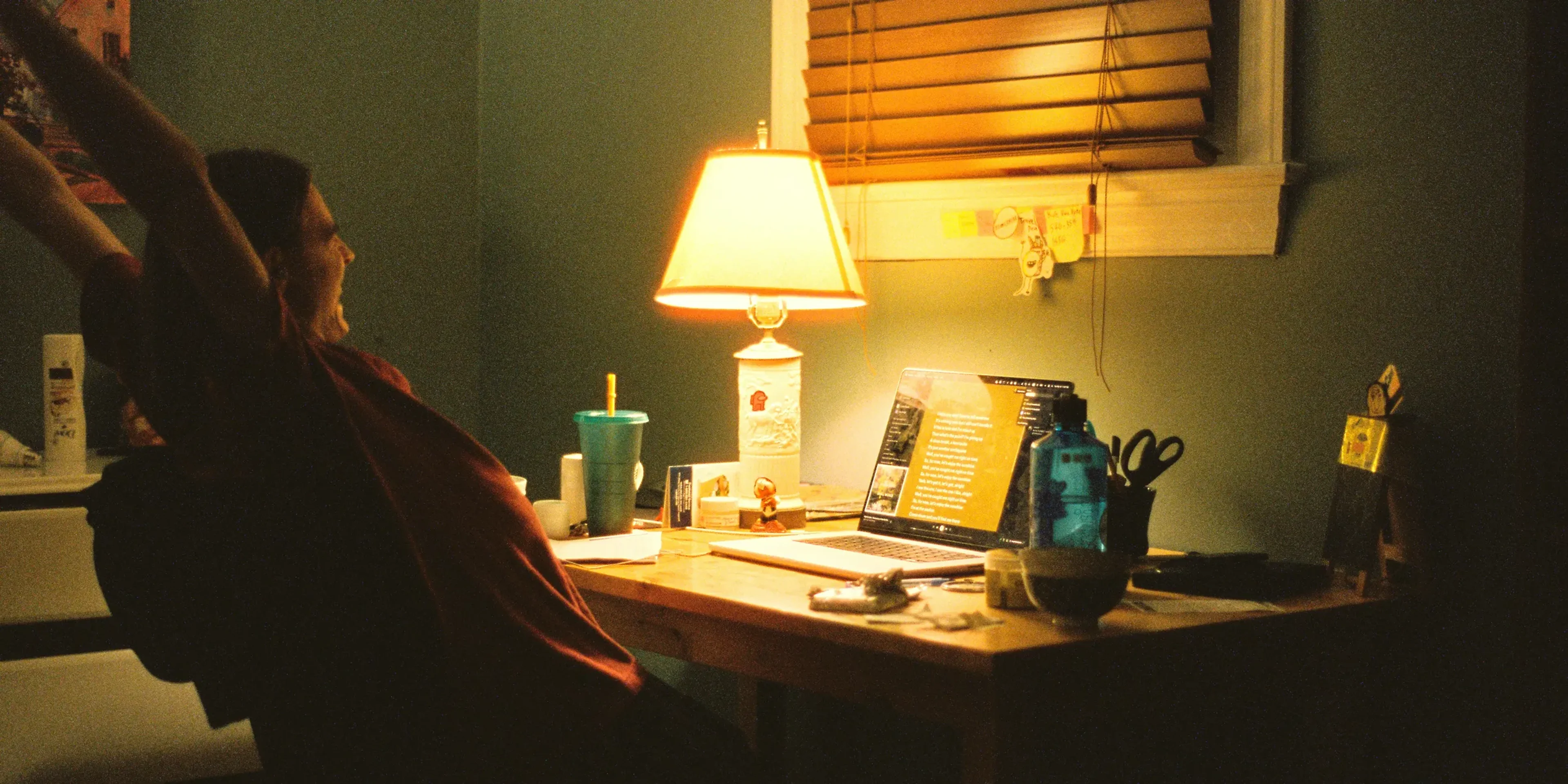 a woman sitting at a desk in front of a lamp