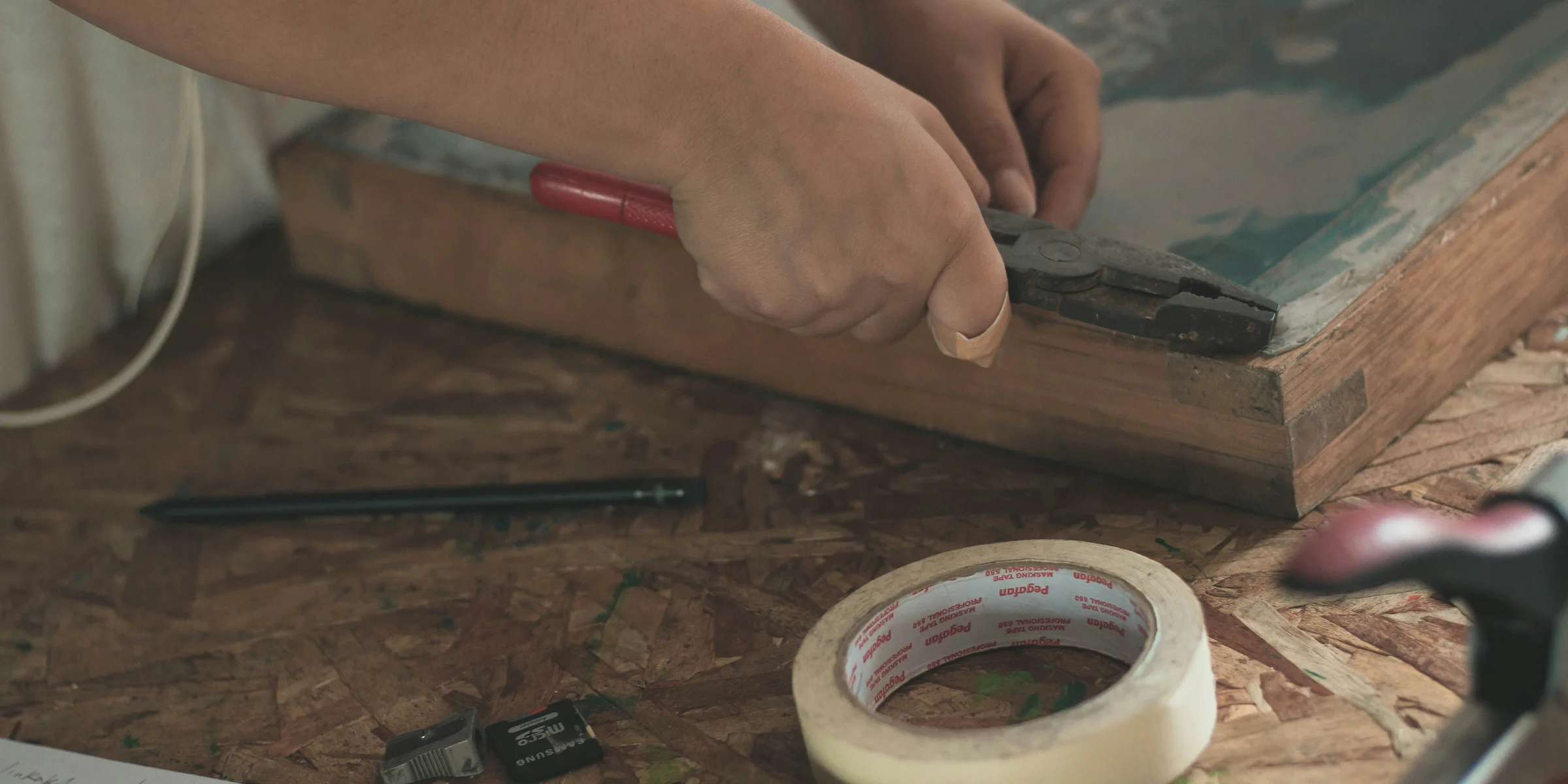 person holding pliers near adhesive tape