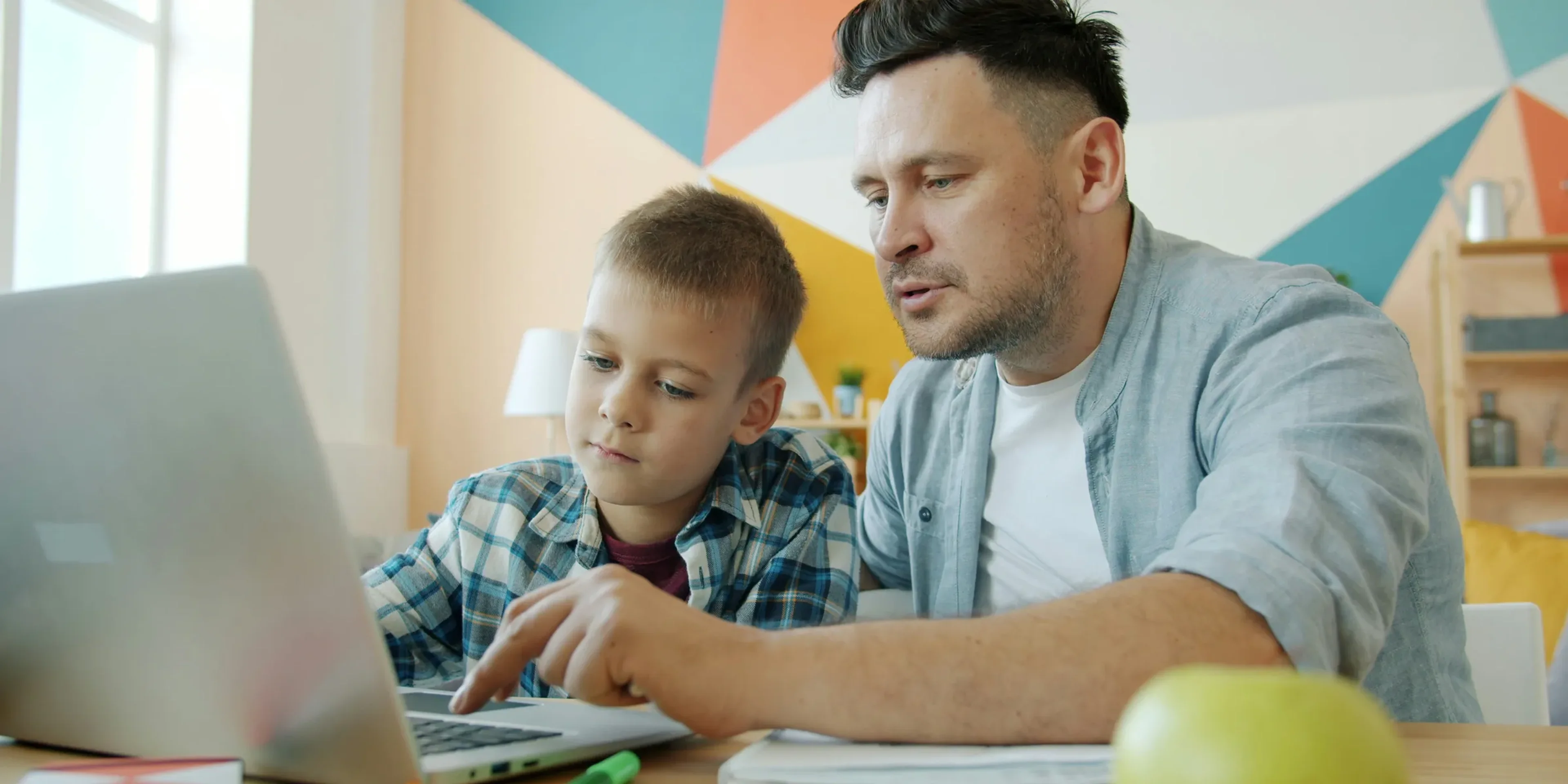 Father and son learning together on a laptop.