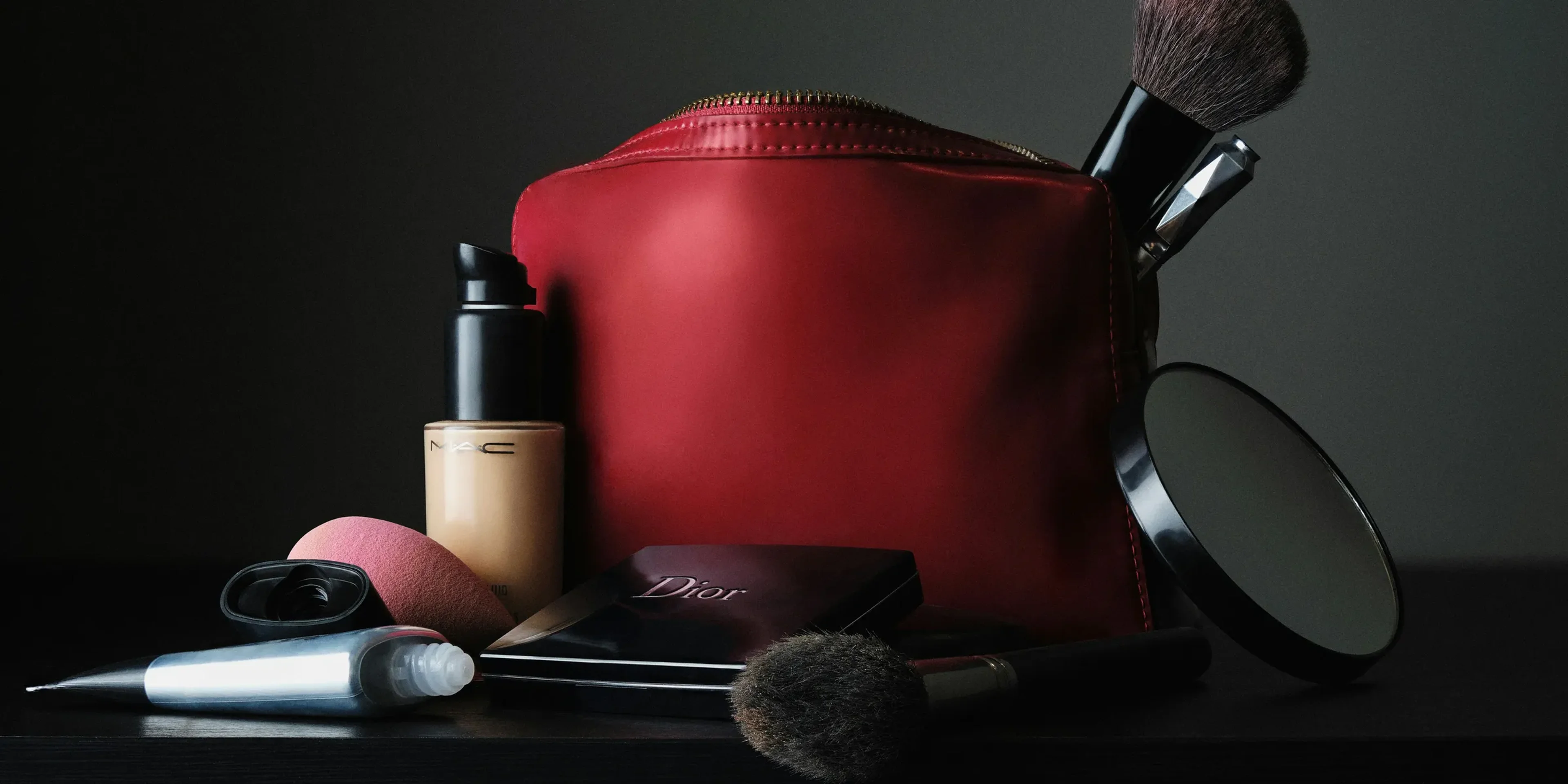 red leather bag beside black makeup brush