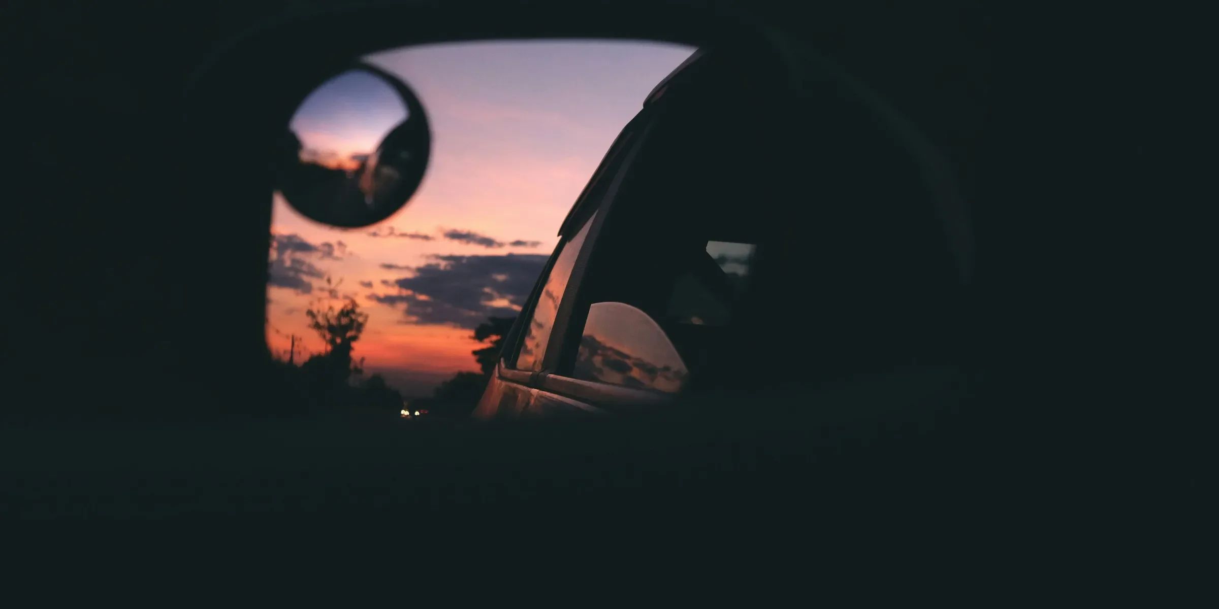 a rear view mirror with a sunset in the background