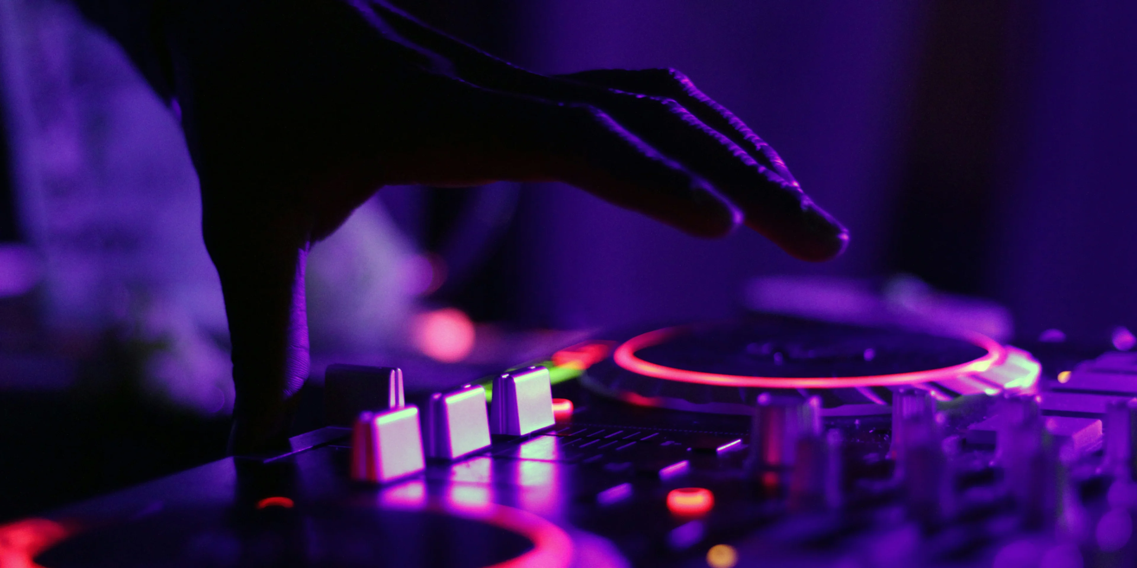 selective focus silhouette photography of man playing red-lighted DJ terminal.