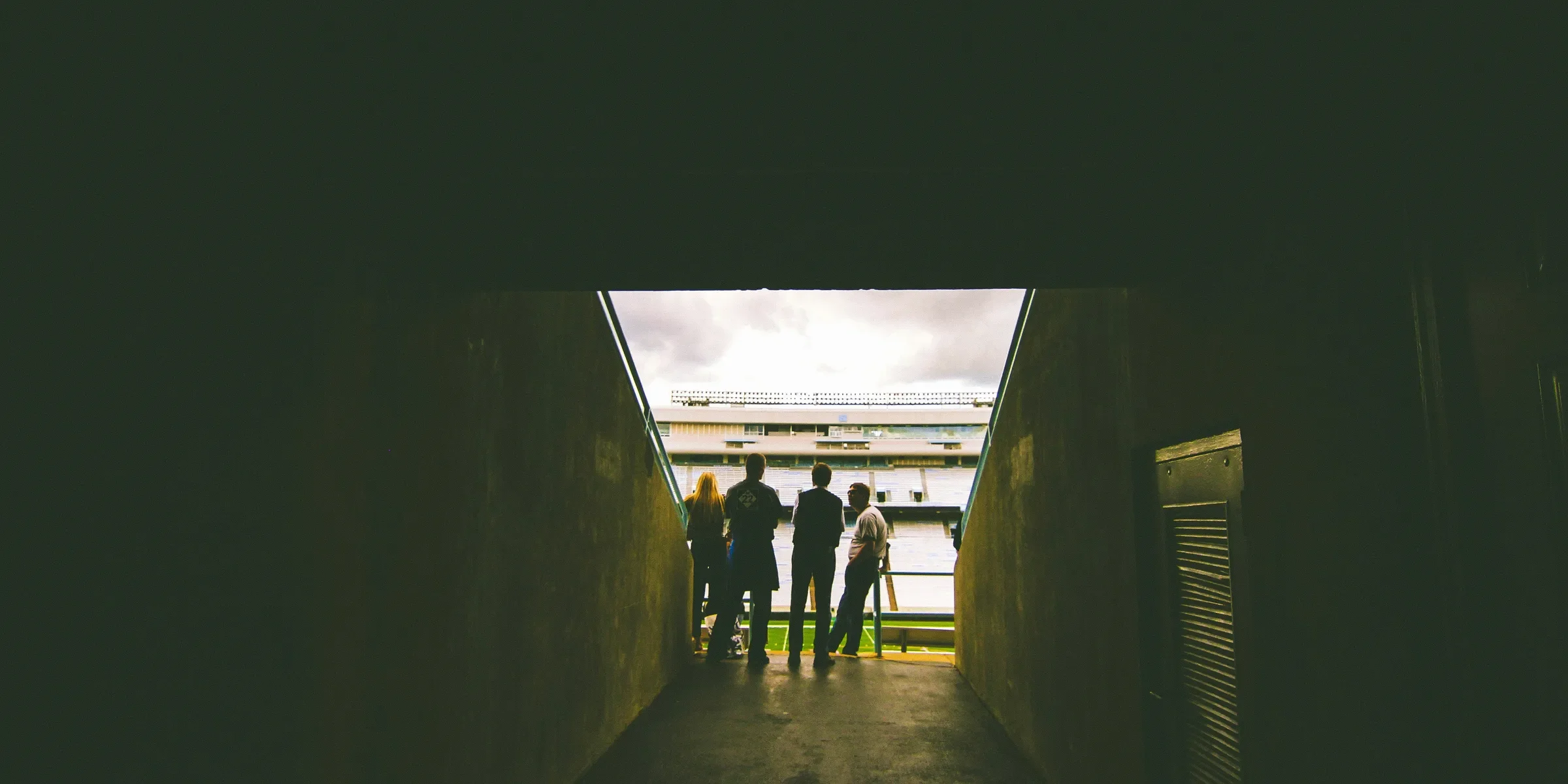 four people standing near gray concrete wall during daytie