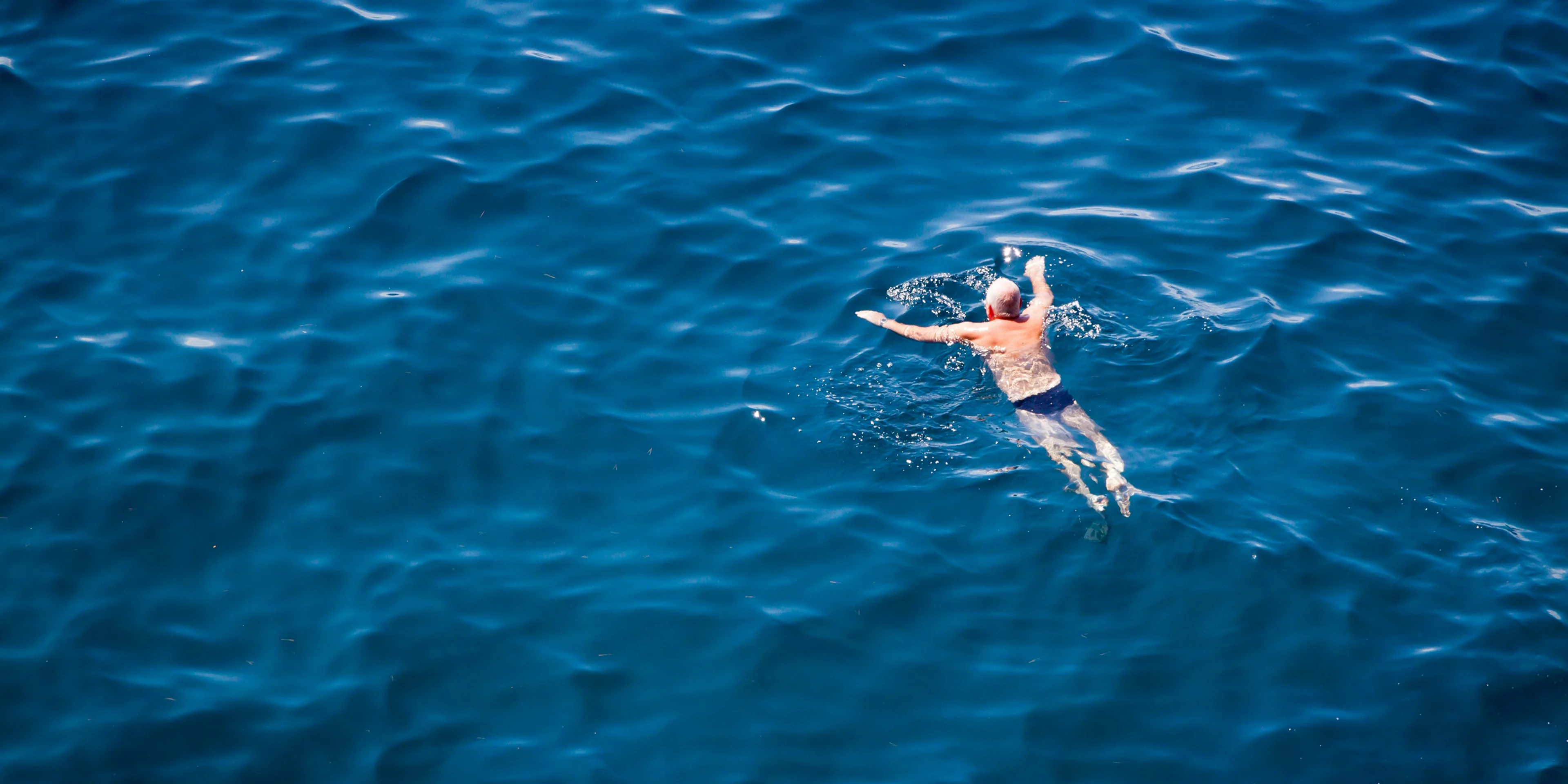 man swimming on body of water.