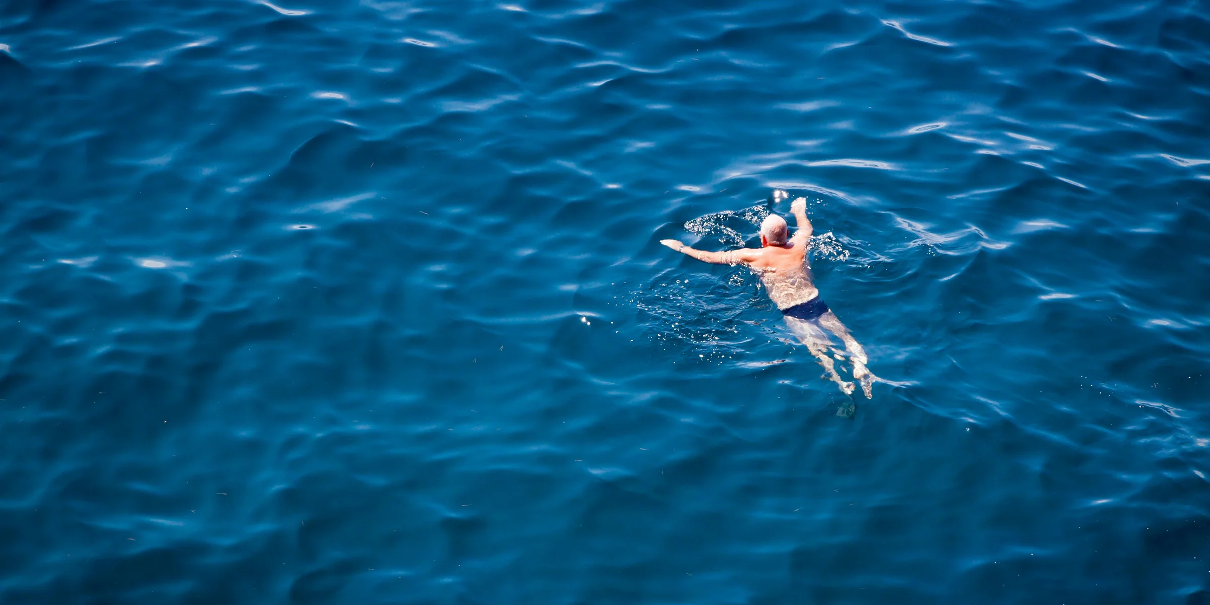 man swimming on body of water.