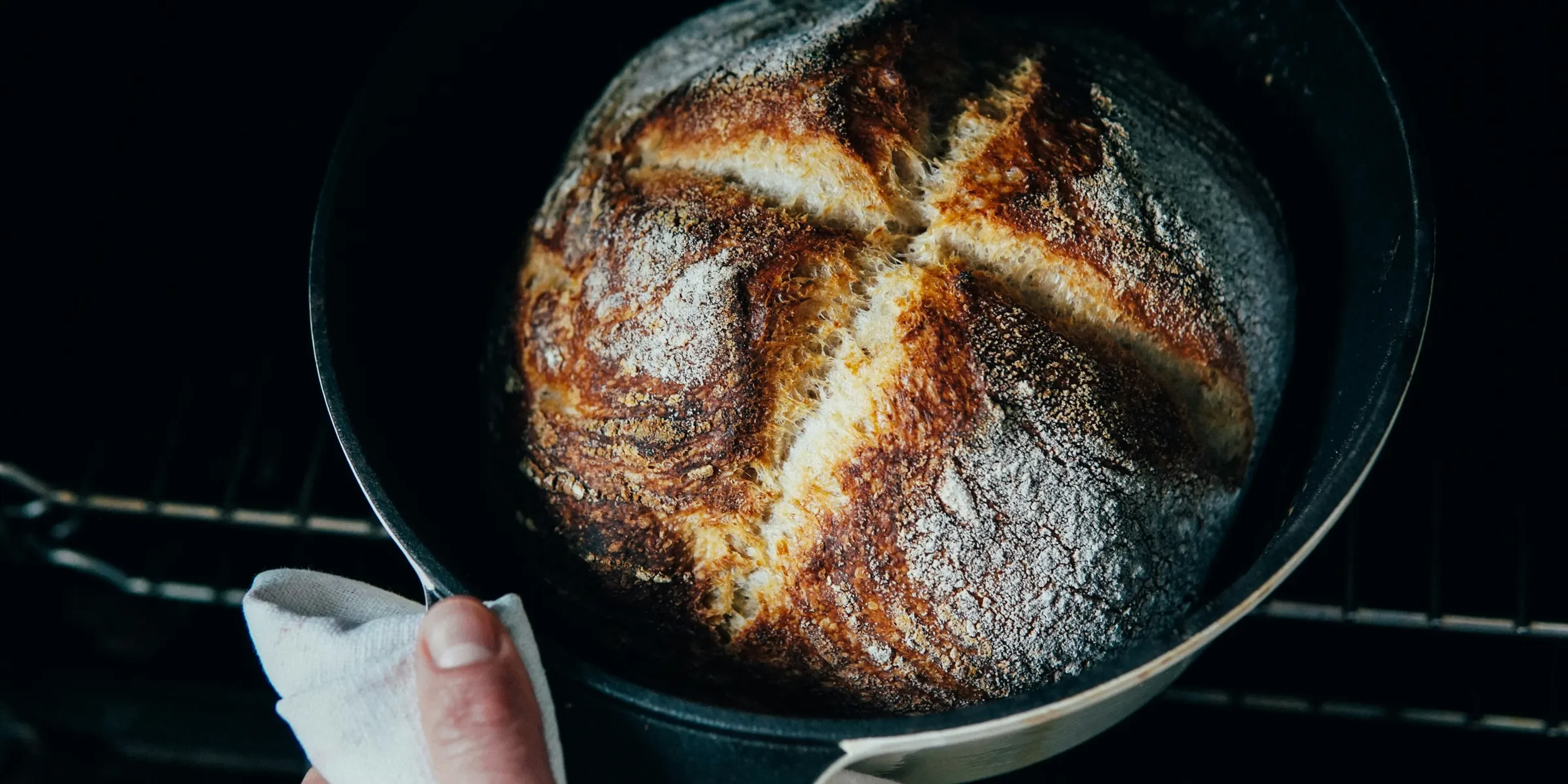 person holding a black round tray with brown bread