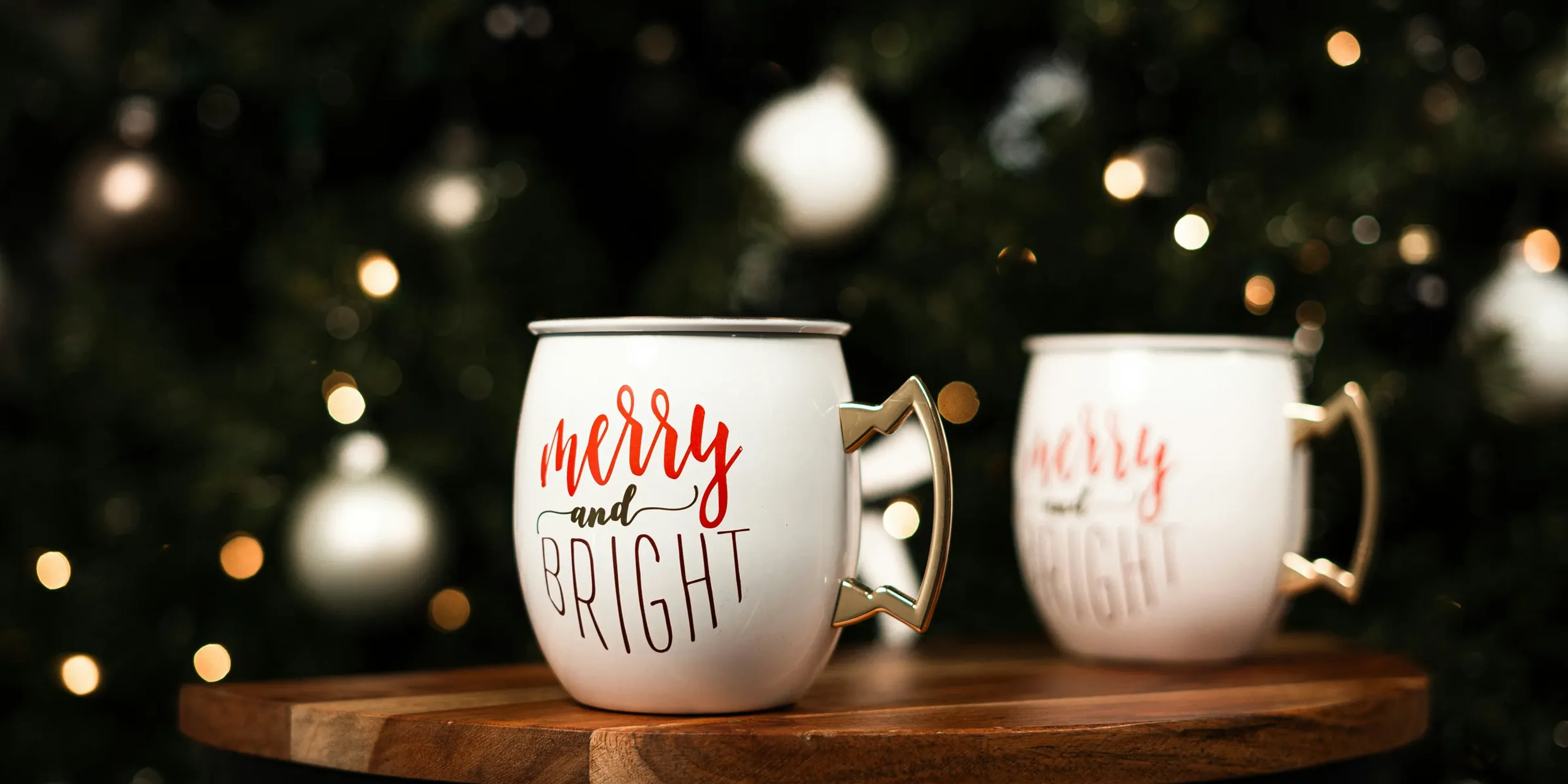 a couple of white mugs with red text on a wooden surface