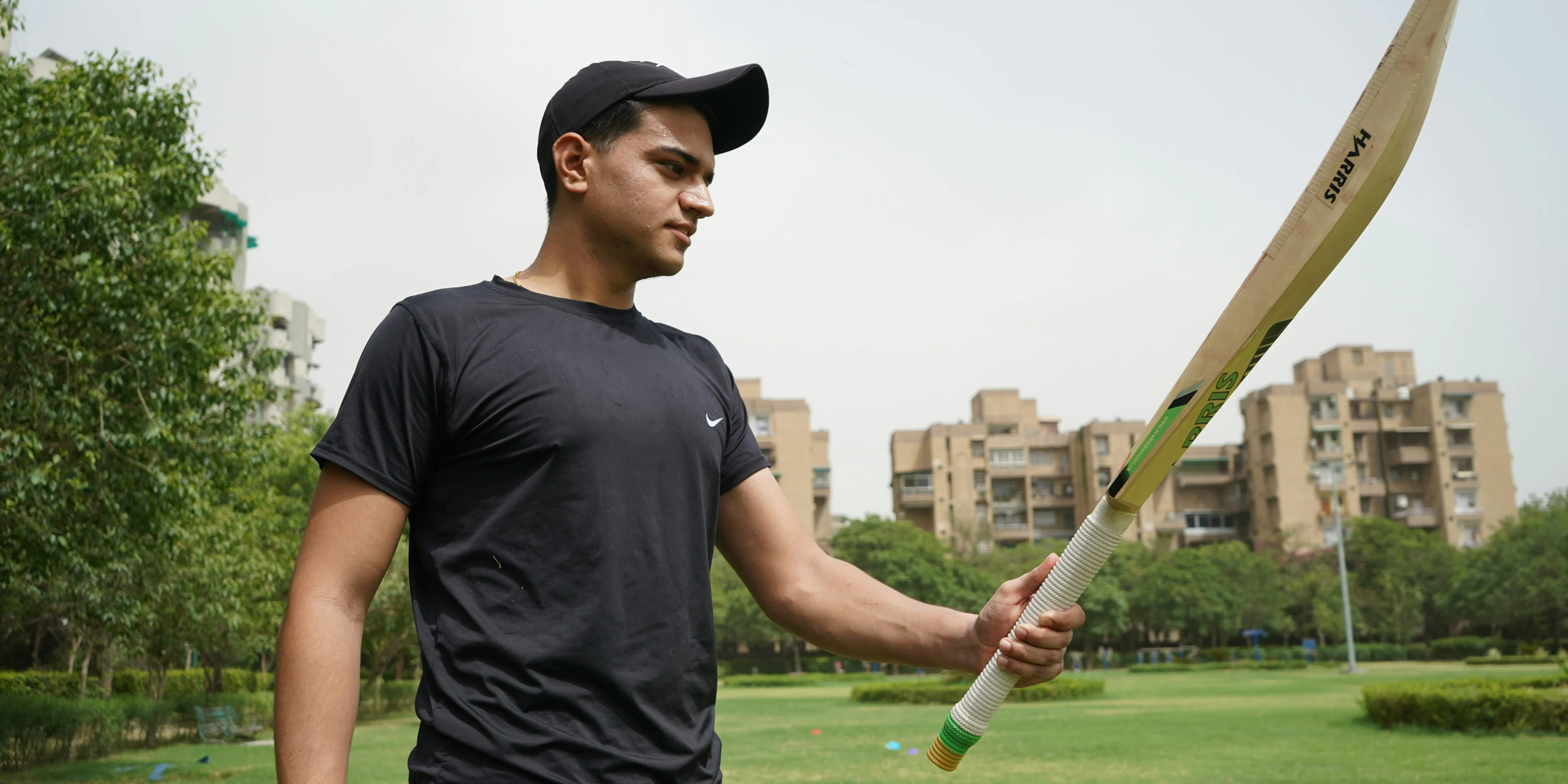 man in black crew neck t-shirt and black cap holding baseball bat