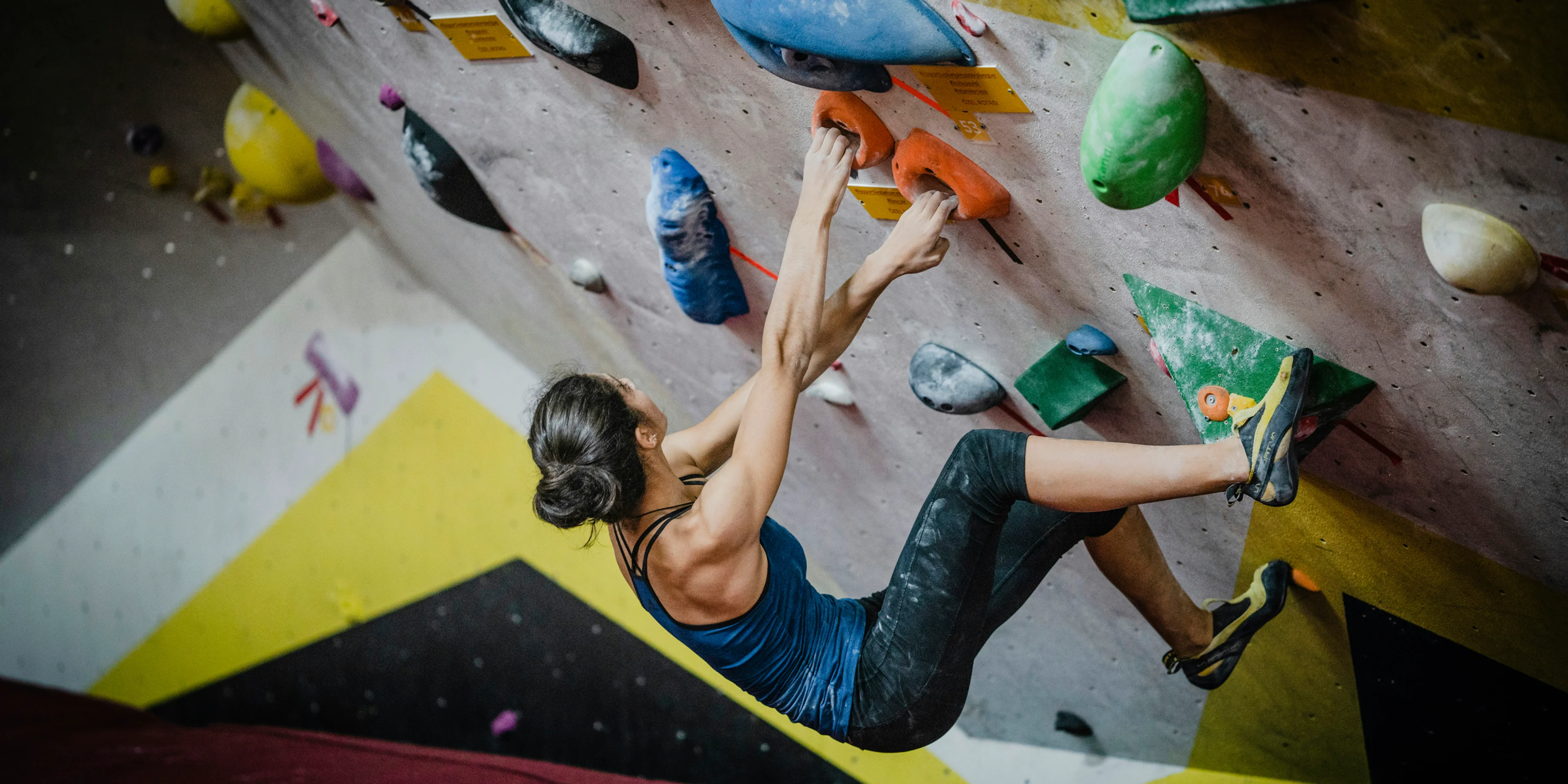 woman rock climbing inside building.